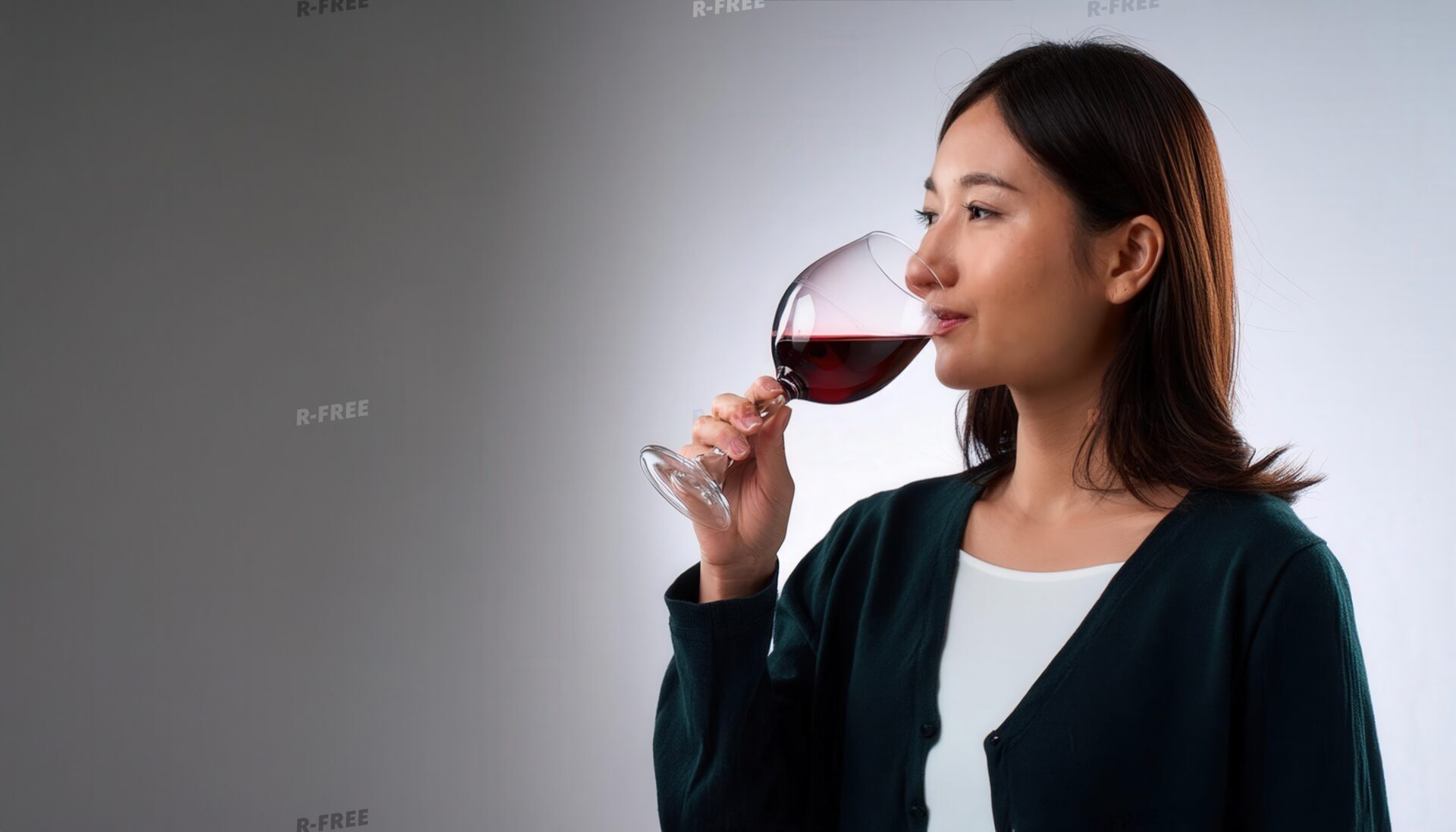 白背景で赤ワインの香りを楽しむ若い女性