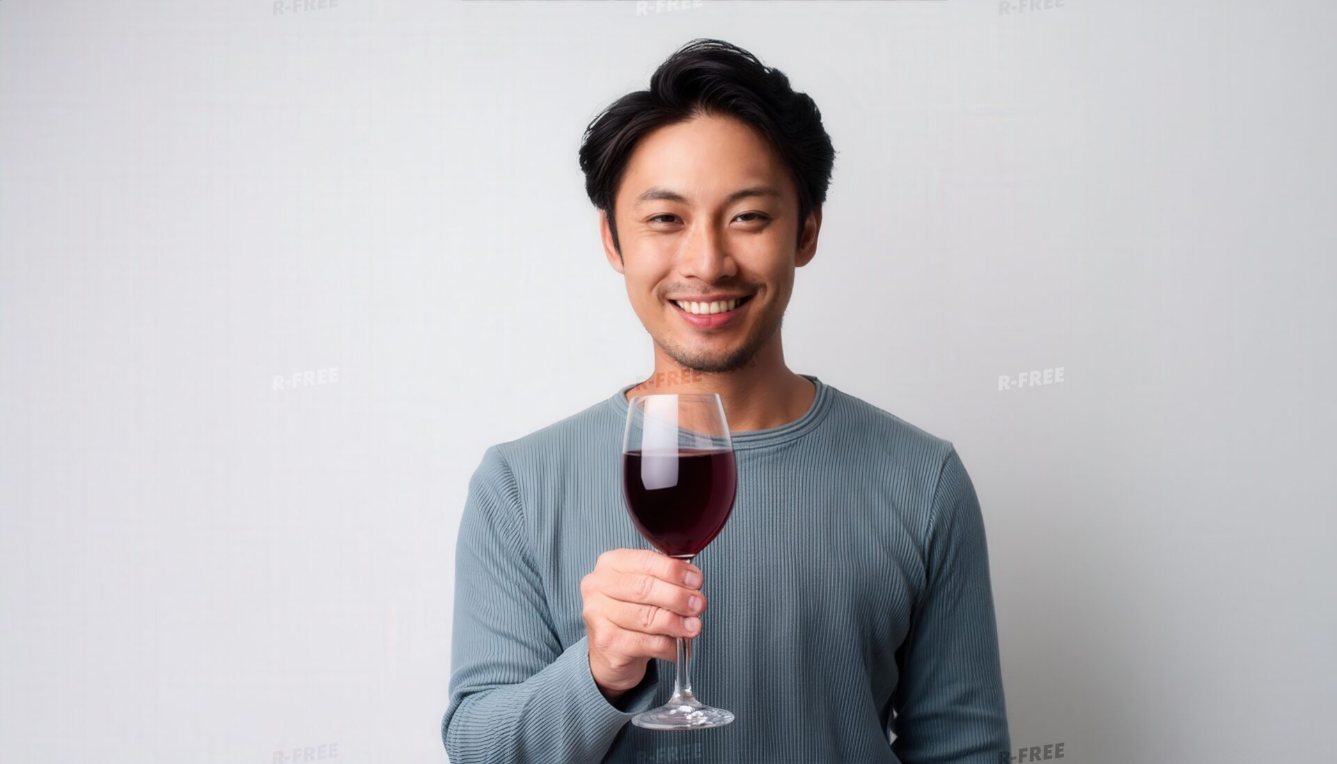 白背景で赤ワインを手に微笑む若い男性