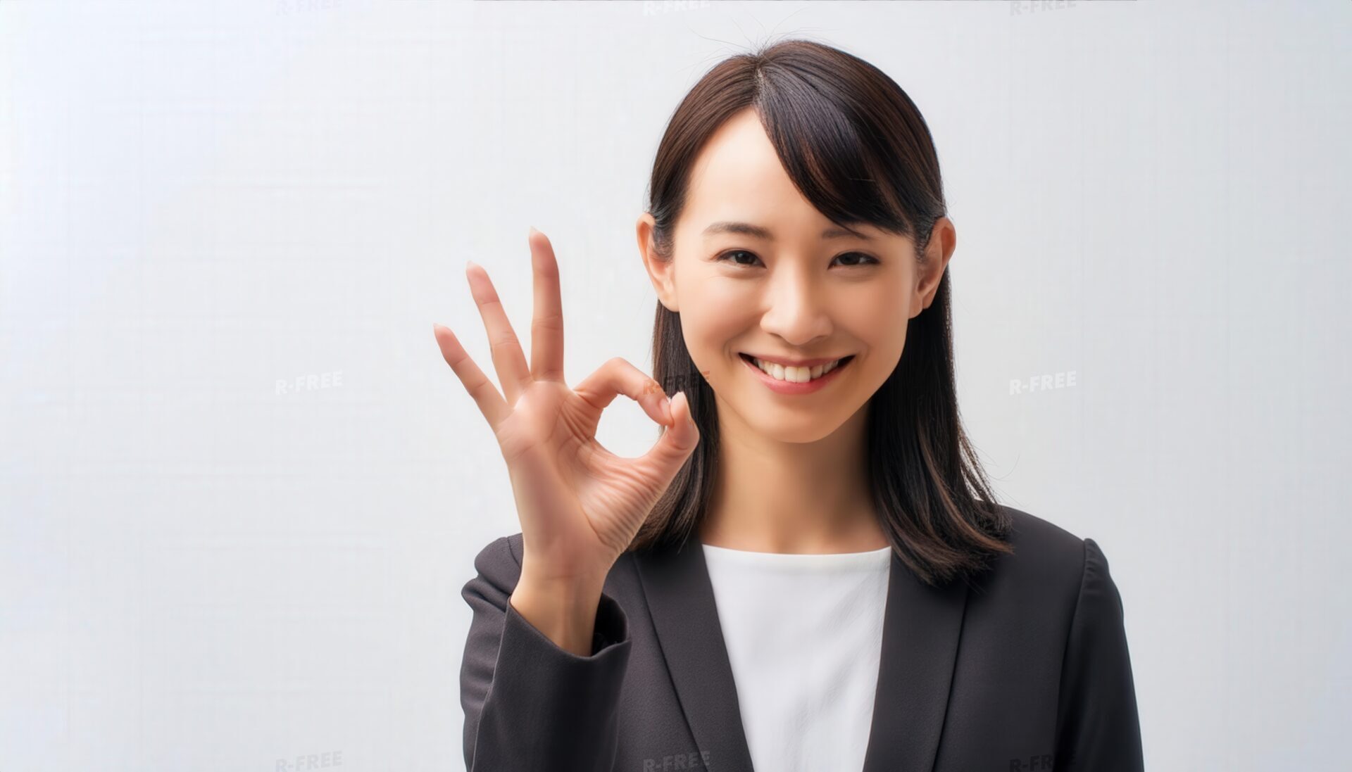 白背景で正面を向きOKサインを示す女性