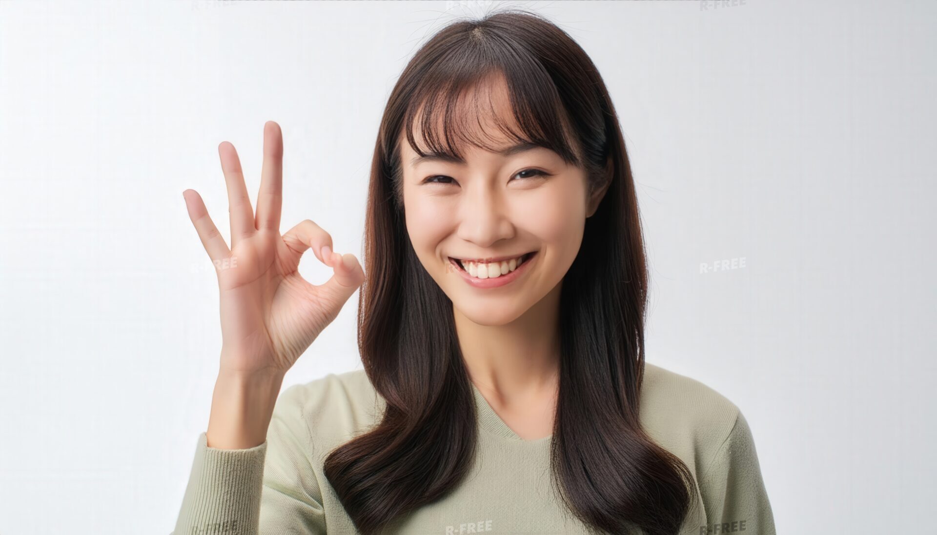 笑顔でOKサインを示す長い黒髪の若い女性
