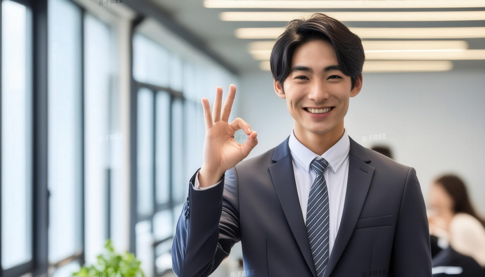 室内でOKサインをするスーツを着た日本人男性