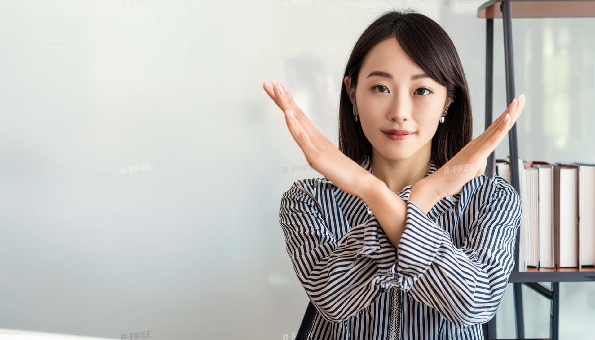 オフィスでストライプシャツを着て腕をクロスしてNGサインを示す人