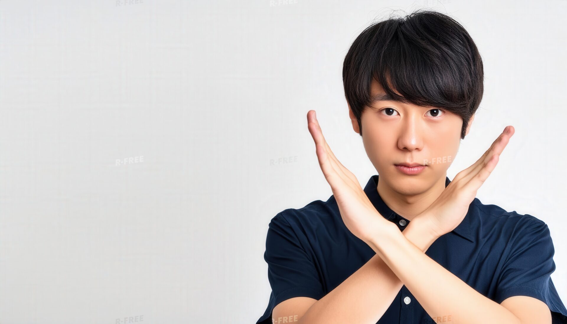 白背景でネイビーのトップスを着て腕をクロスする真剣な表情の人