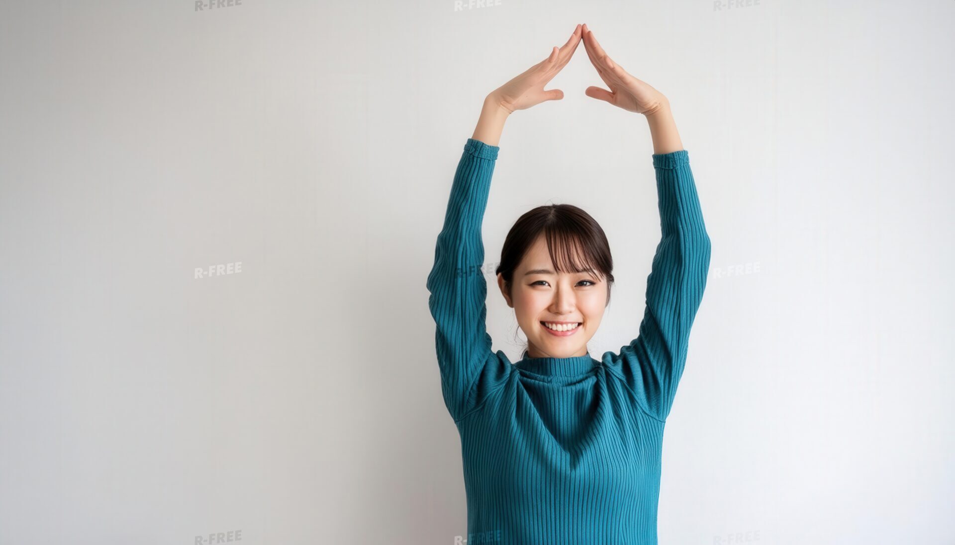緑色のセーターで頭上に円を作っている若い人