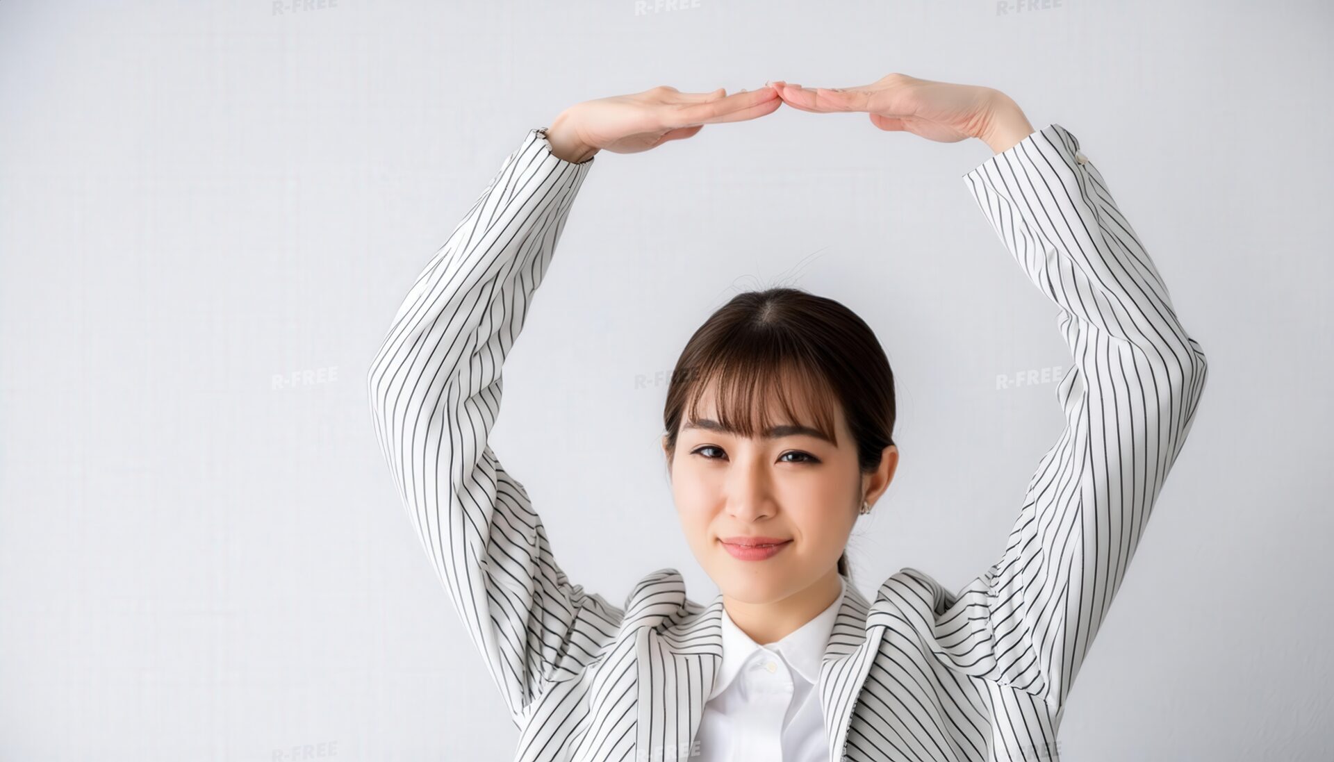 ストライプのジャケットで頭上に円を作っている若い人