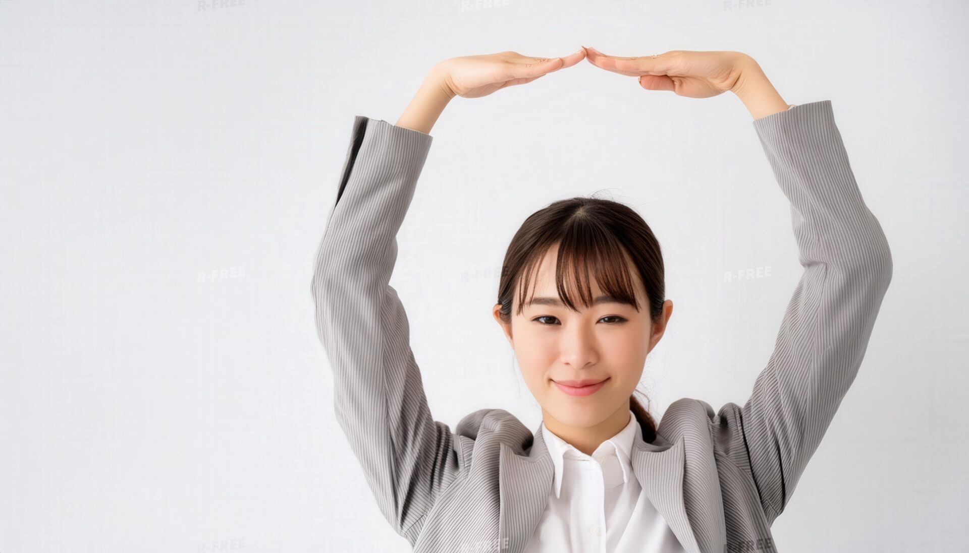 薄いグレーのスーツで頭上に円を作っている若い人