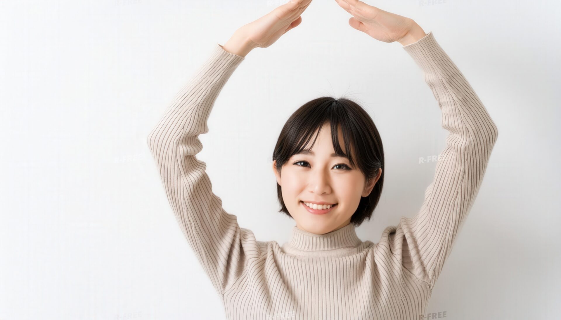 リブ編みセーターで頭上に円を作る笑顔の20代女性