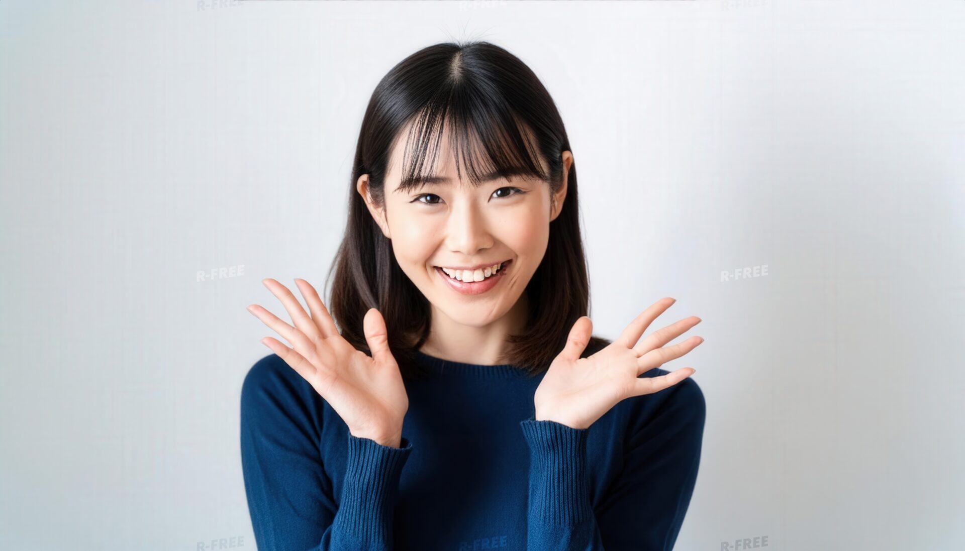 白背景で両手を広げるネイビートップスを着た若い女性