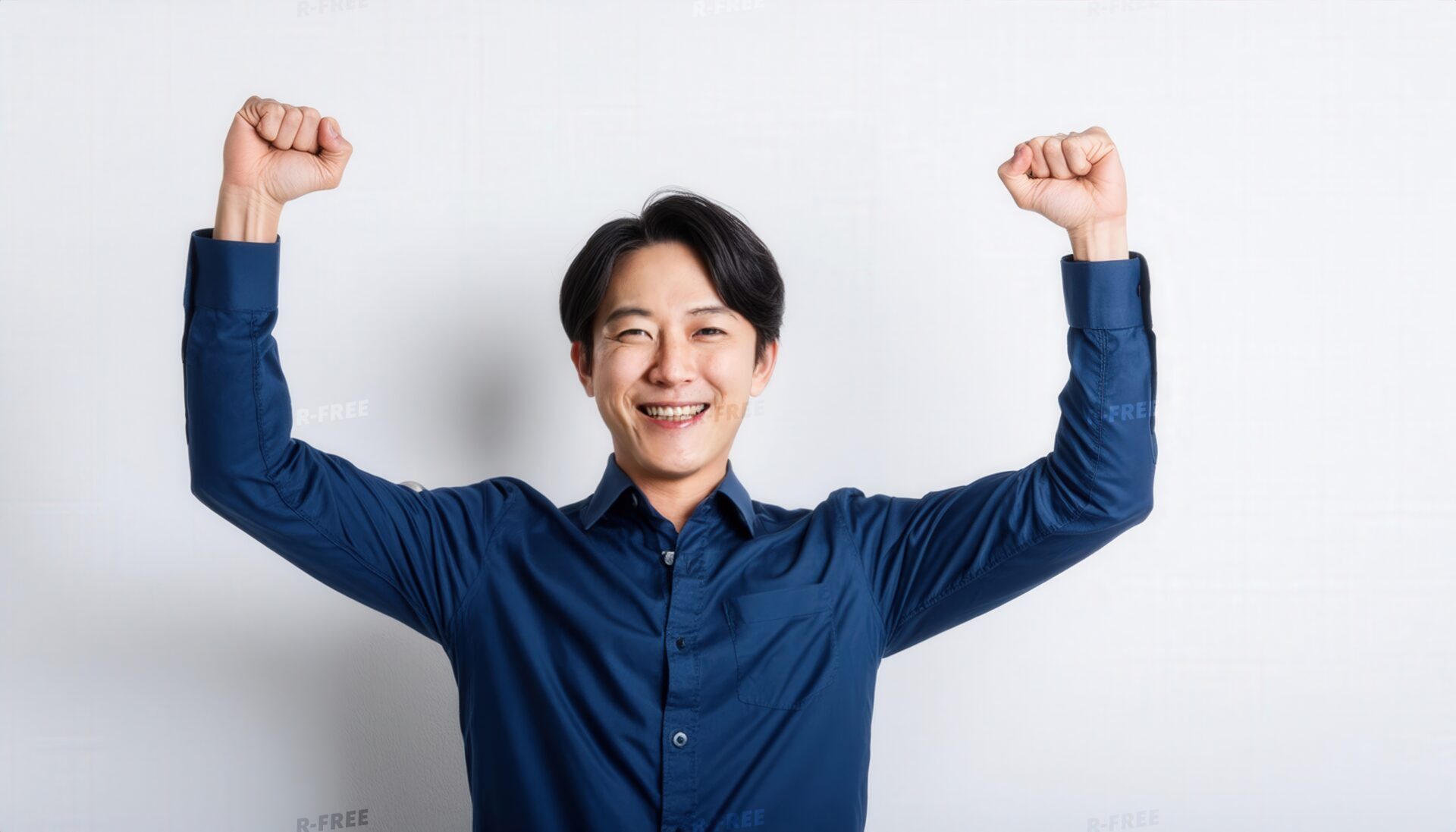 白背景で拳を上げる笑顔の若い男性（ネイビーシャツ）