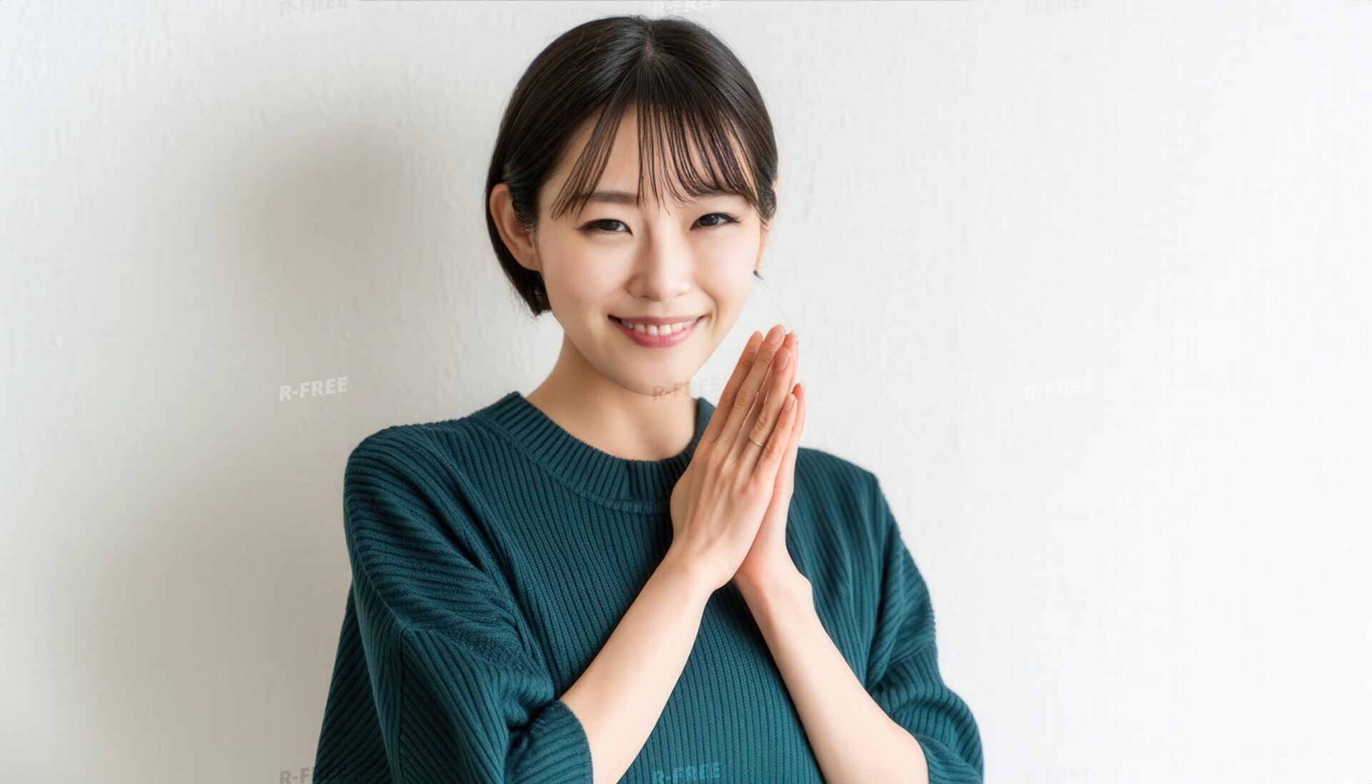 合掌する深緑ニットの若い女性と穏やかな笑顔