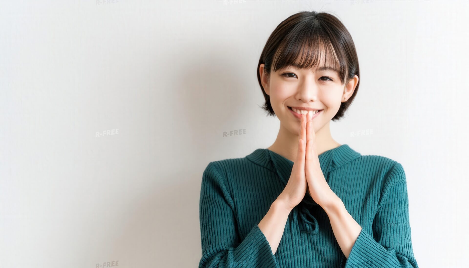 白背景で笑顔で合掌するショートヘアの若い女性