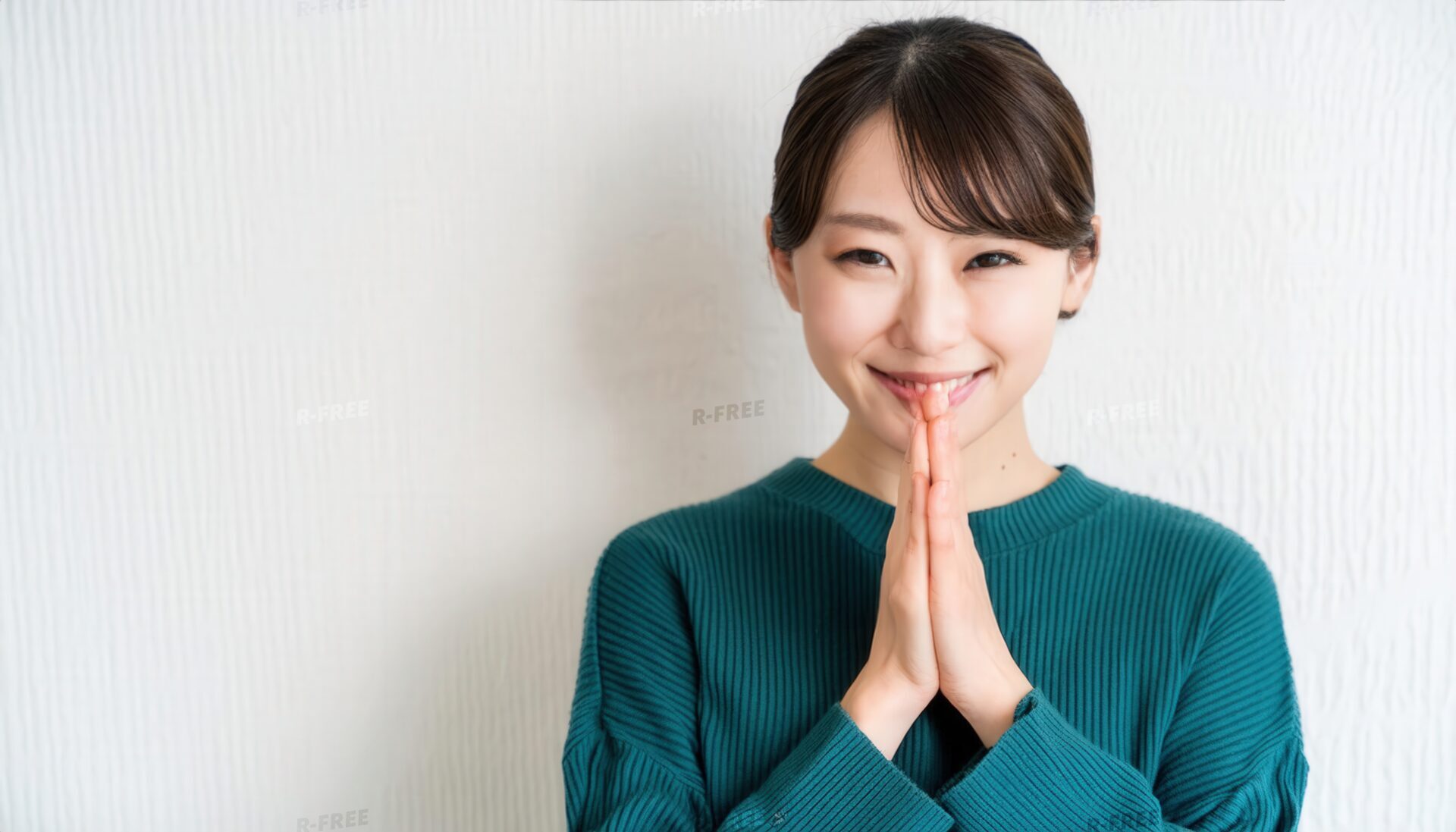 合掌して微笑む髪をまとめた30代の女性
