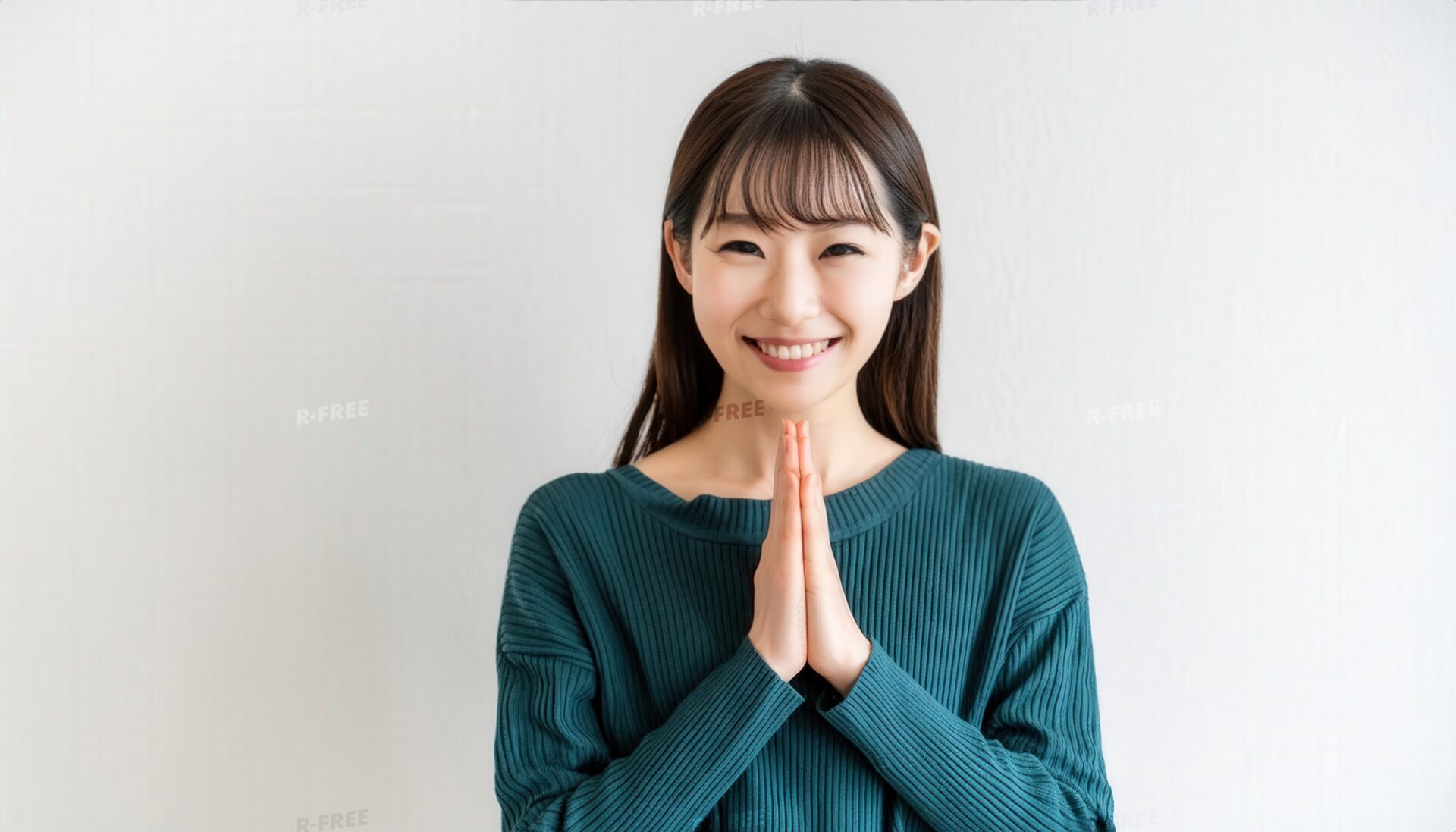 白背景で胸元に合掌するロングヘアの若い女性