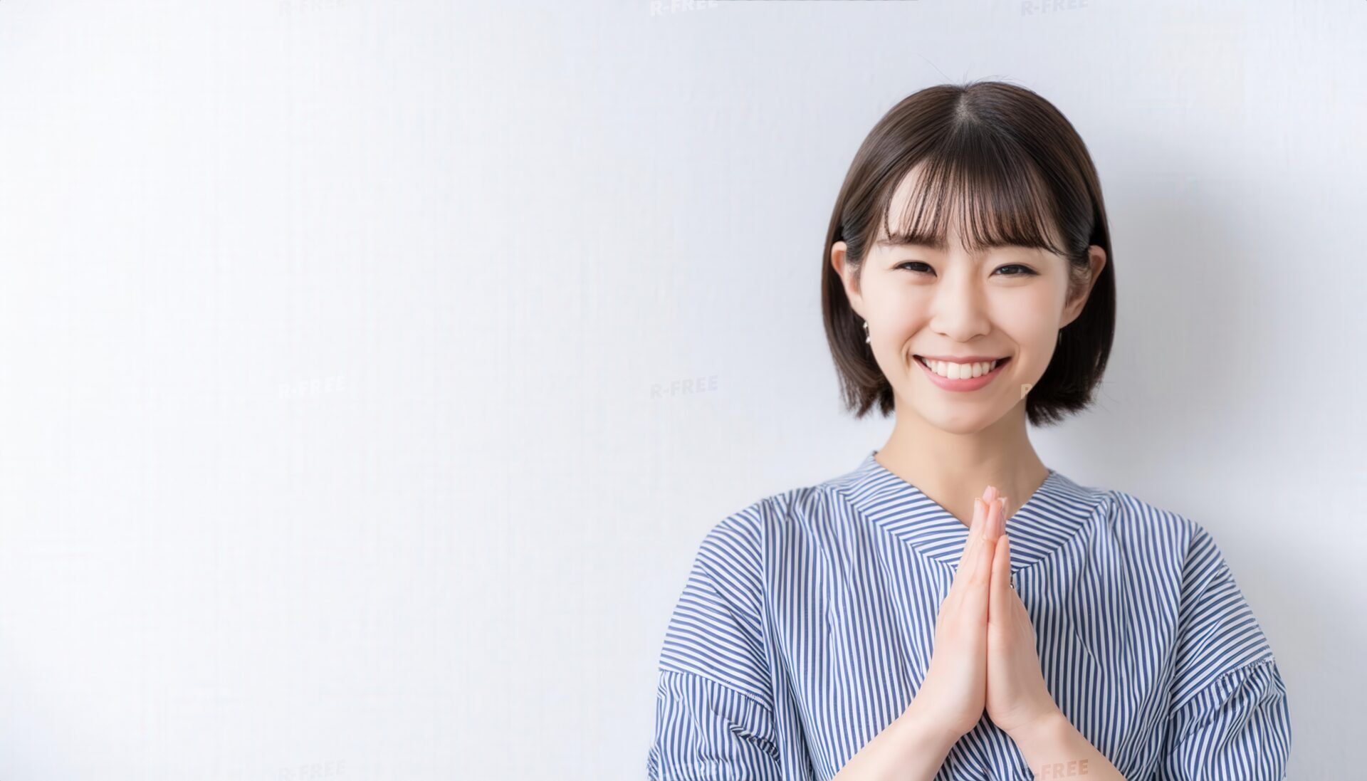 白背景で祈りのポーズをとる若い女性