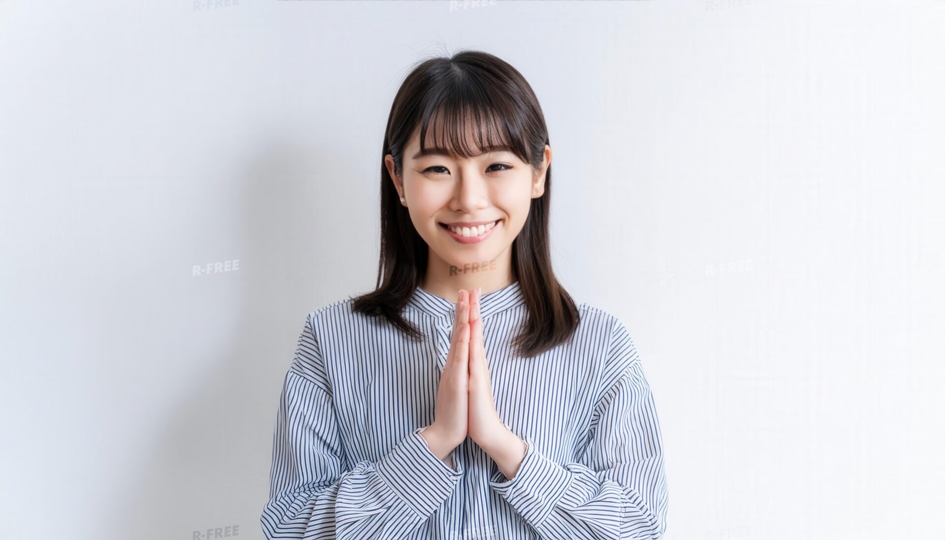 白背景で合掌する若い女性（ストライプシャツ）
