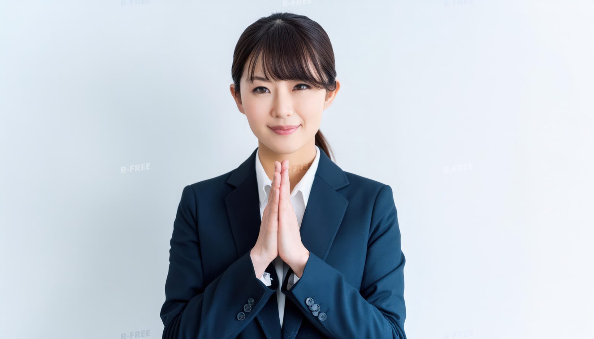 合掌して穏やかな表情を浮かべる20代女性スーツ