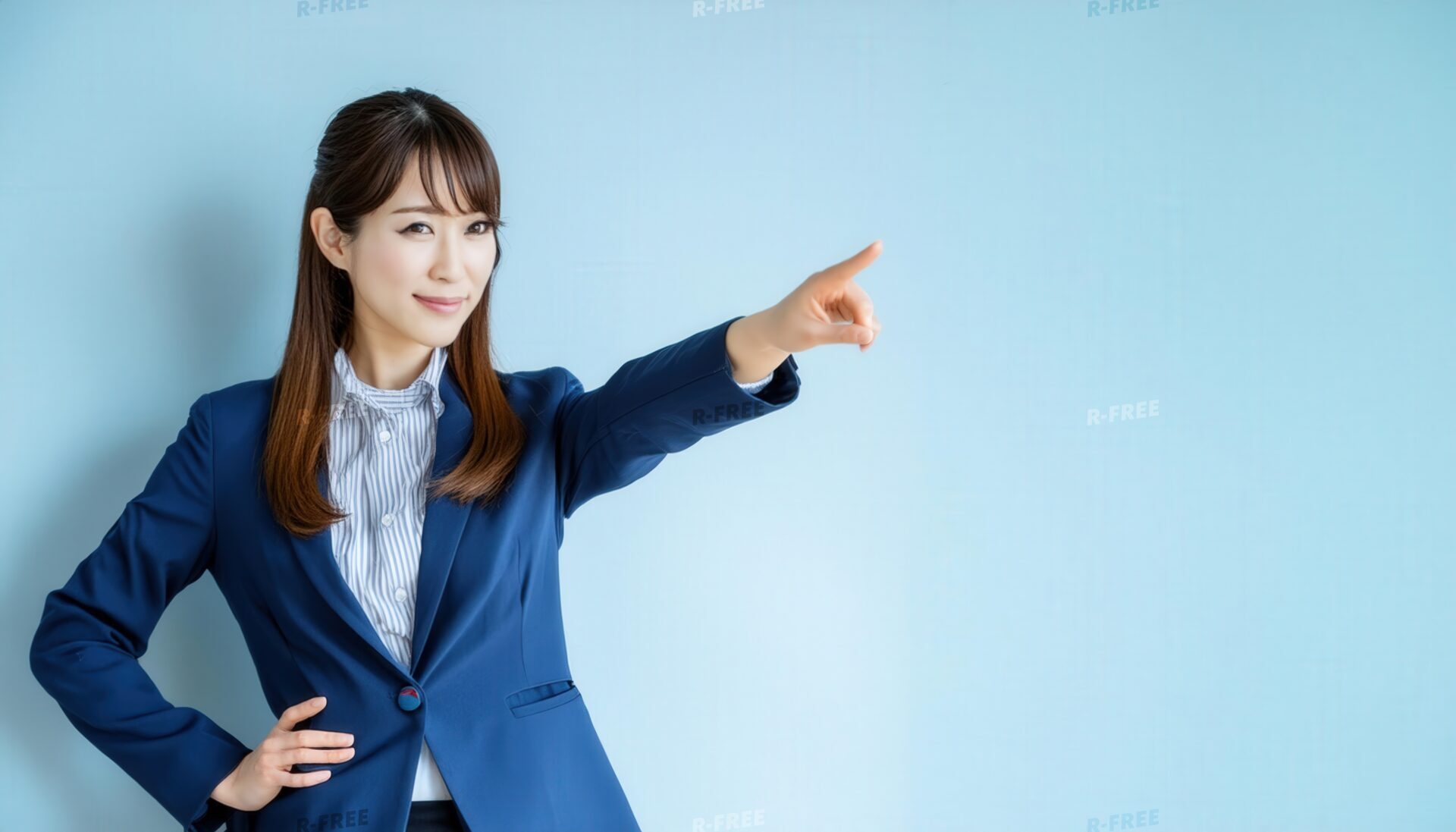 水色の背景でスーツ姿の若い人が笑顔で前方を指をさす