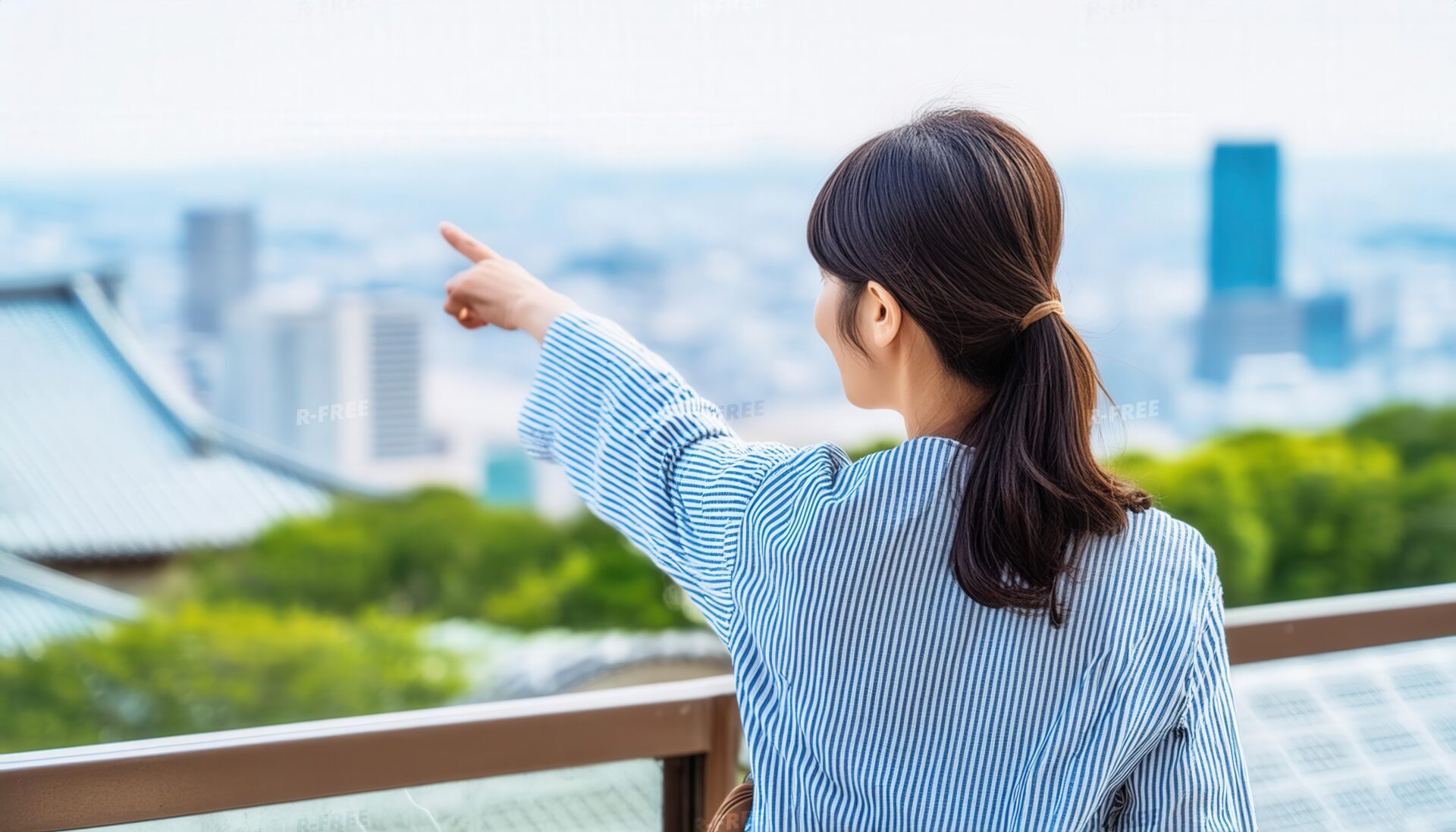 ストライプのトップスを着た後ろ姿の若い人が街を指す