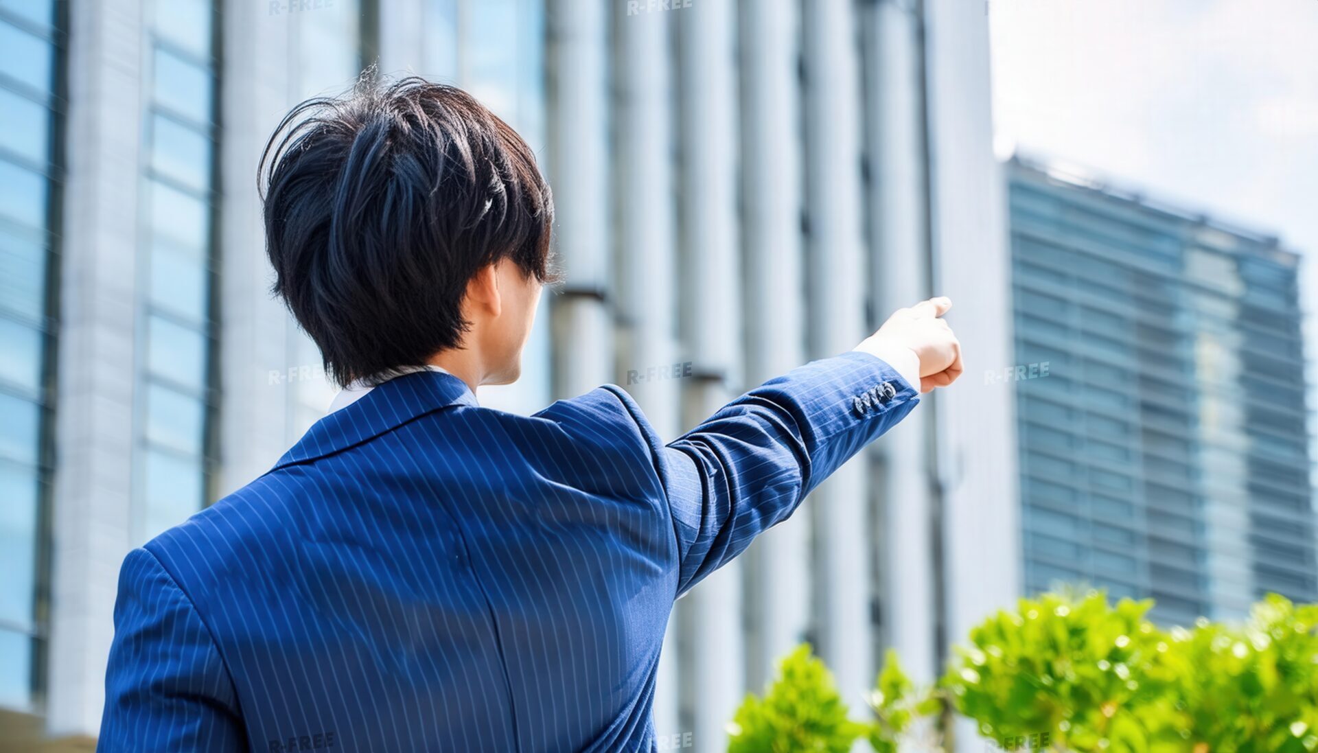 ビジネス街で指をさす後ろ姿の若い男性