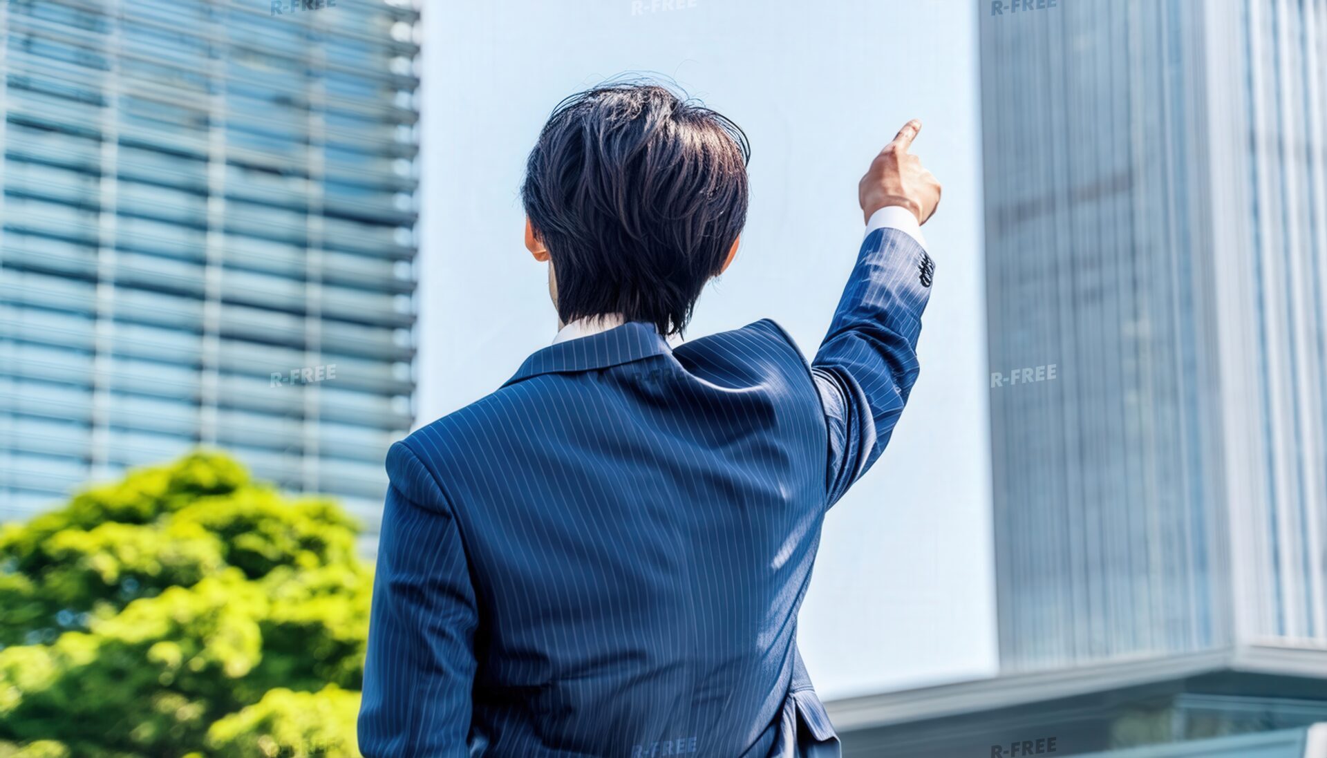 大きなビルを指さす後ろ姿の若い男性