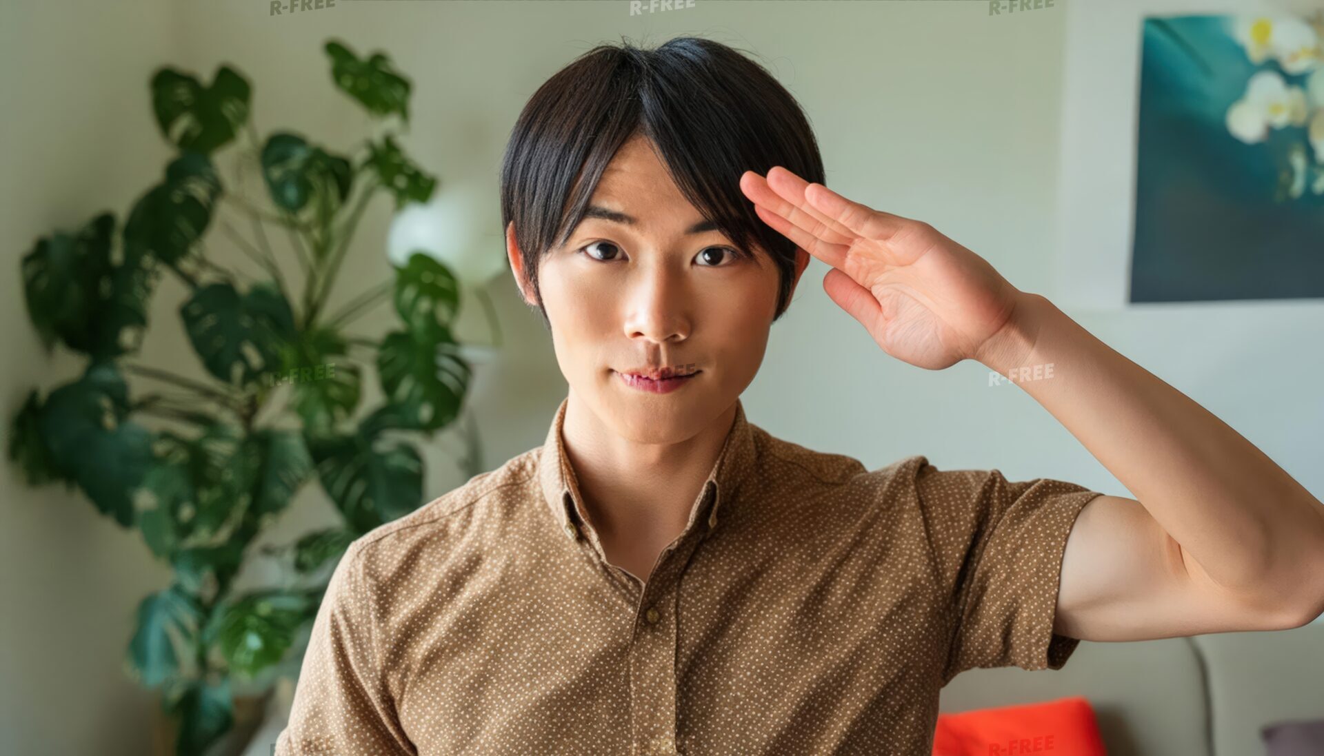 茶色の半袖シャツで穏やかに敬礼する20代男性