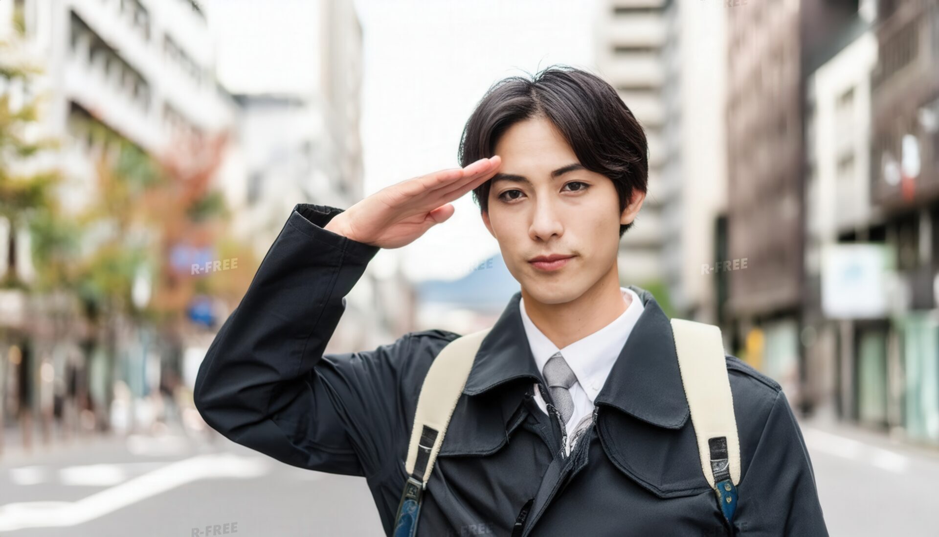 街中で敬礼する白シャツとネクタイ姿の男性