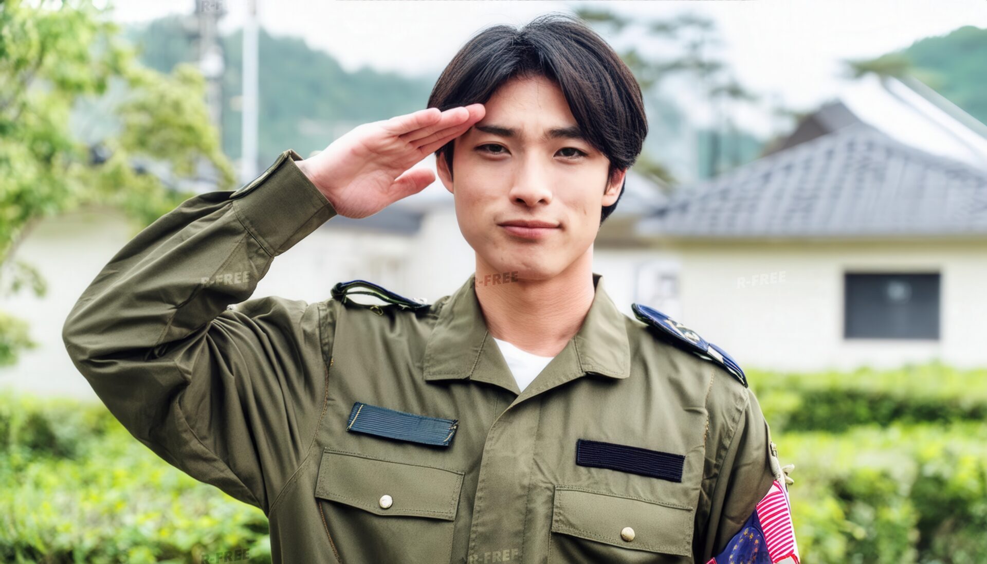 屋外で敬礼する軍人・オリーブ色制服の若い男性と緑の植栽