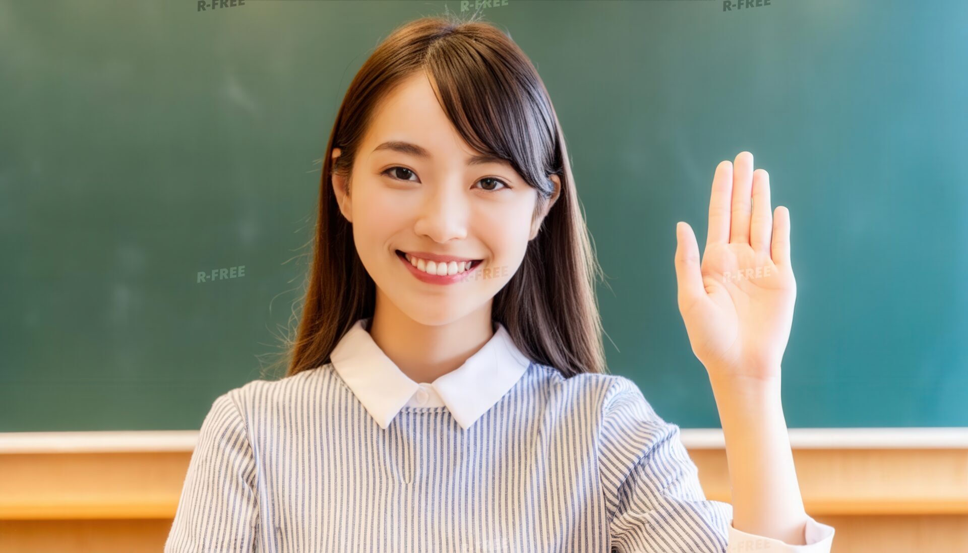 教壇を背景に挙手するストライプシャツの笑顔の学生