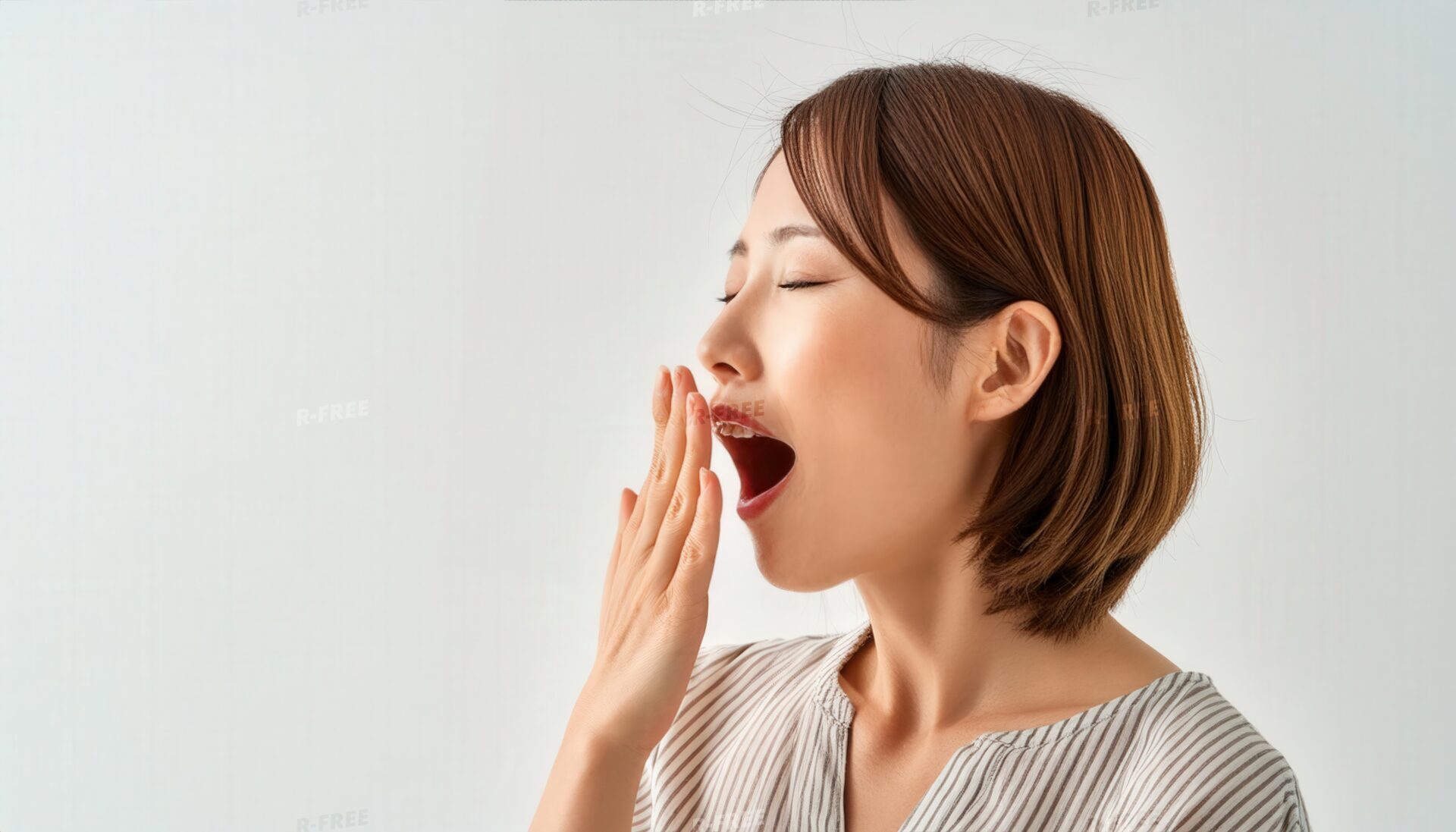 白背景であくびをする女性