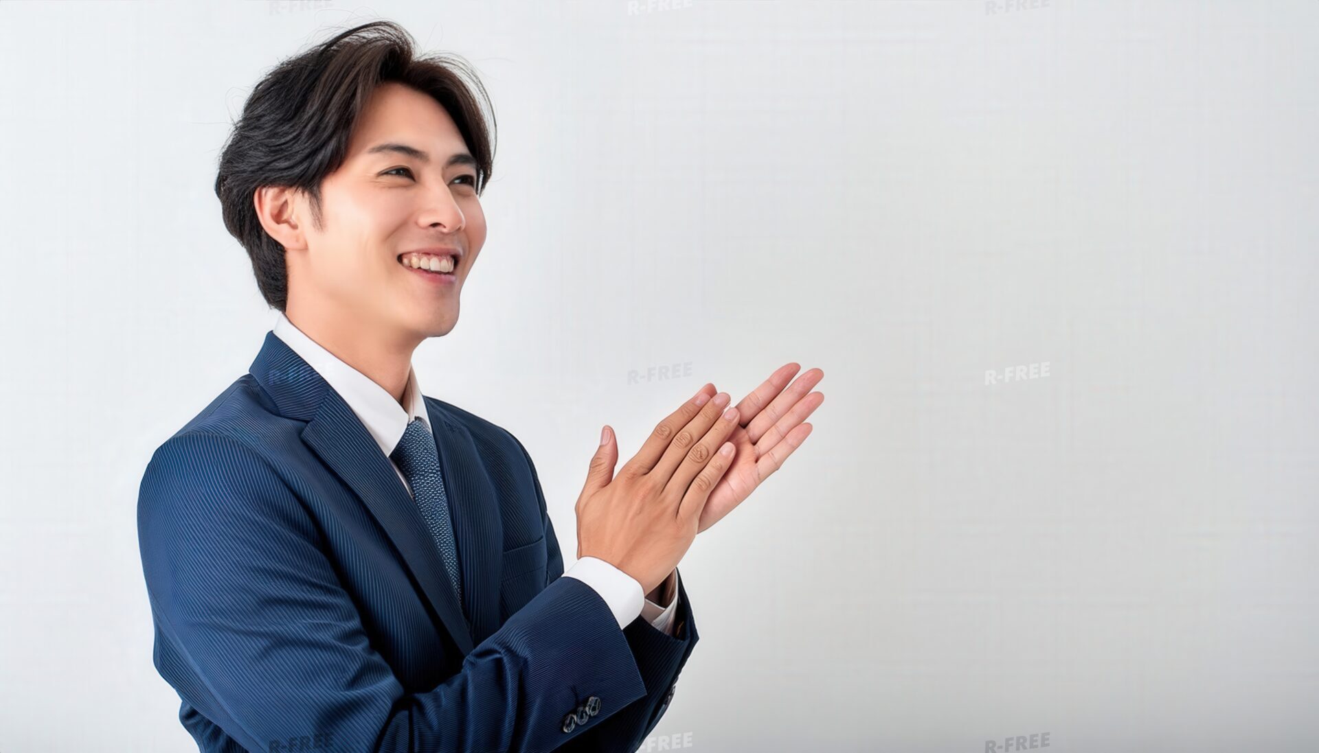斜め上を見て笑顔で拍手する20代日本人男性