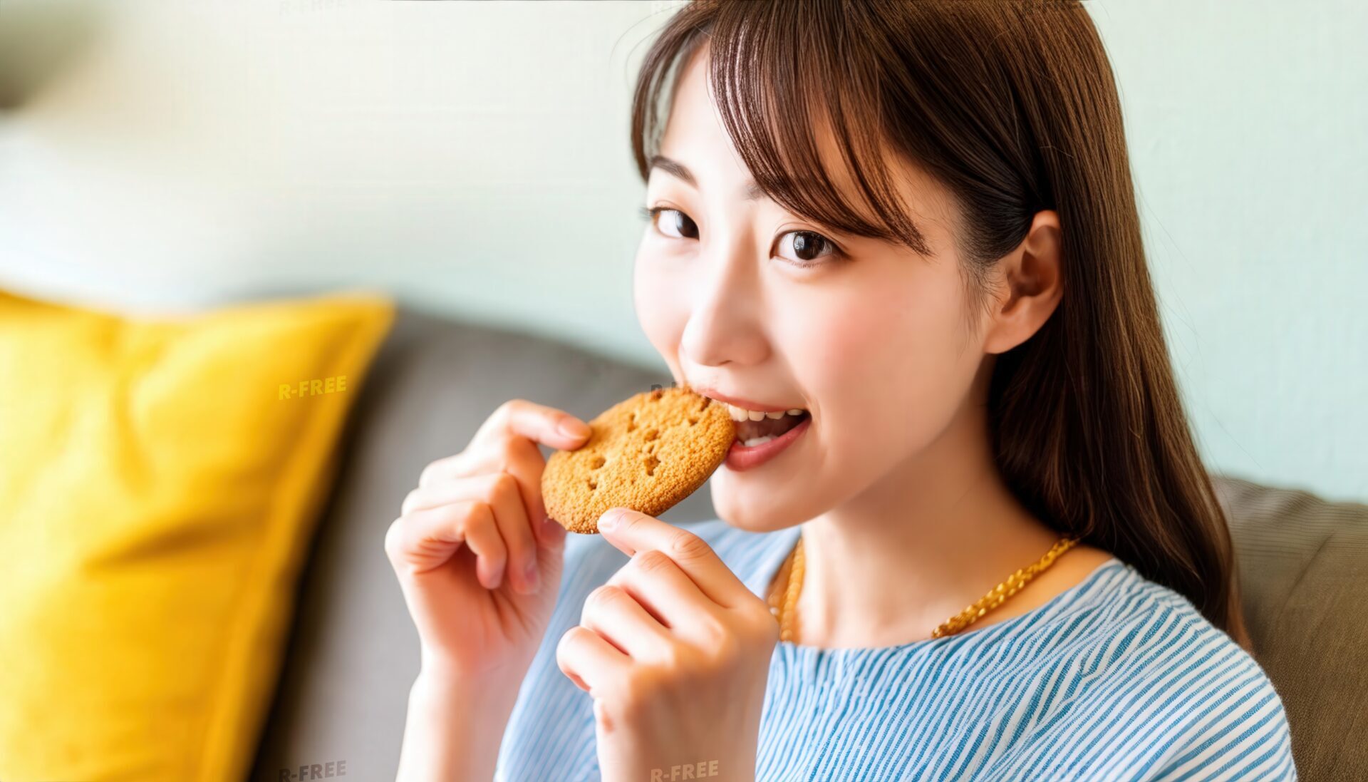 青いストライプ服で笑顔でクッキーを食べる女性