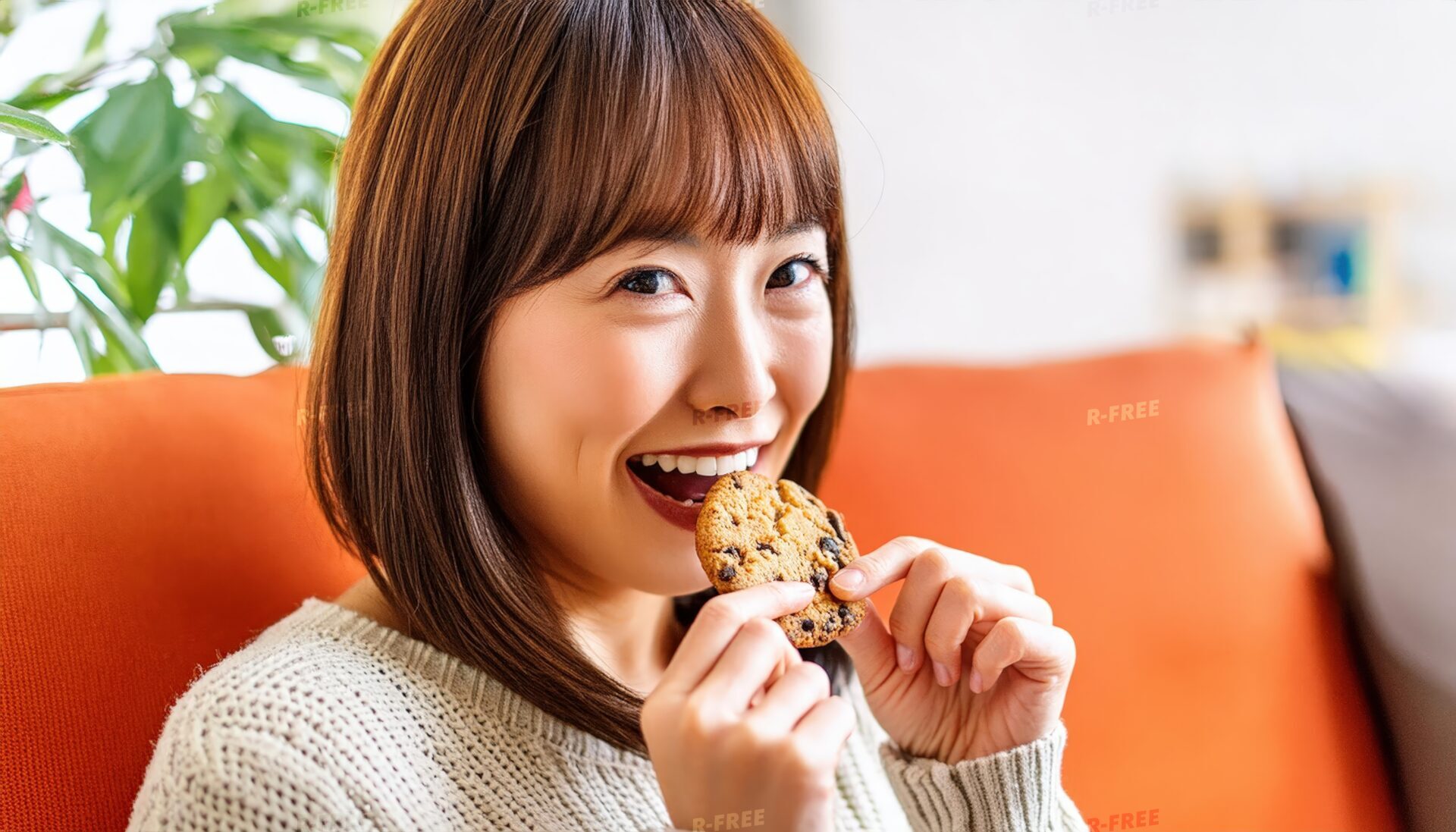 白いニットでチョコチップクッキーを食べる女性