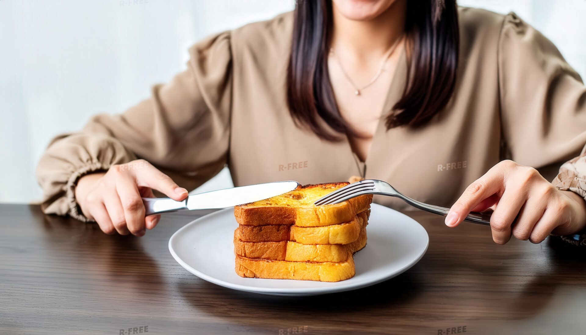 フレンチトーストを食べる女性・ベージュブラウスと木目調テーブルの朝食