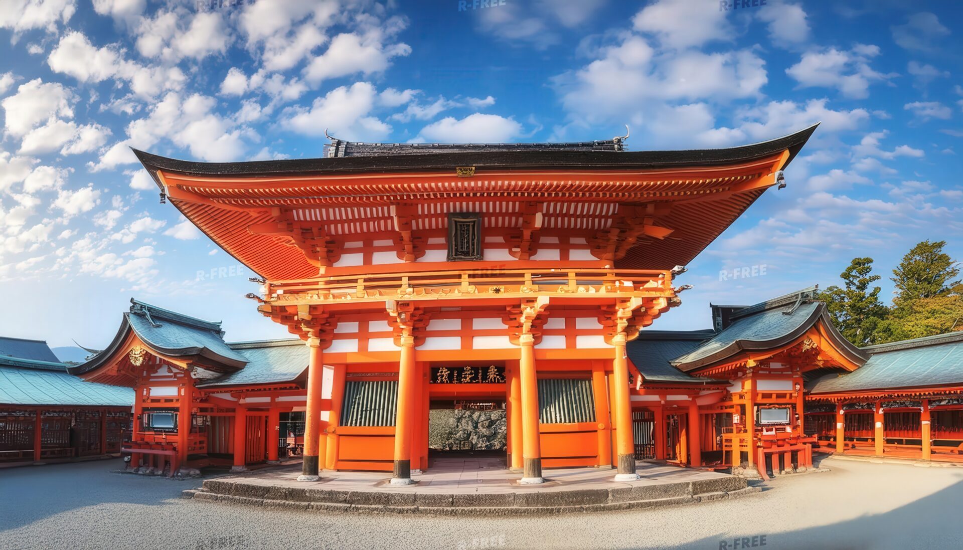 翼廊付きの大きな門と石畳が広がる朱色の寺院正面