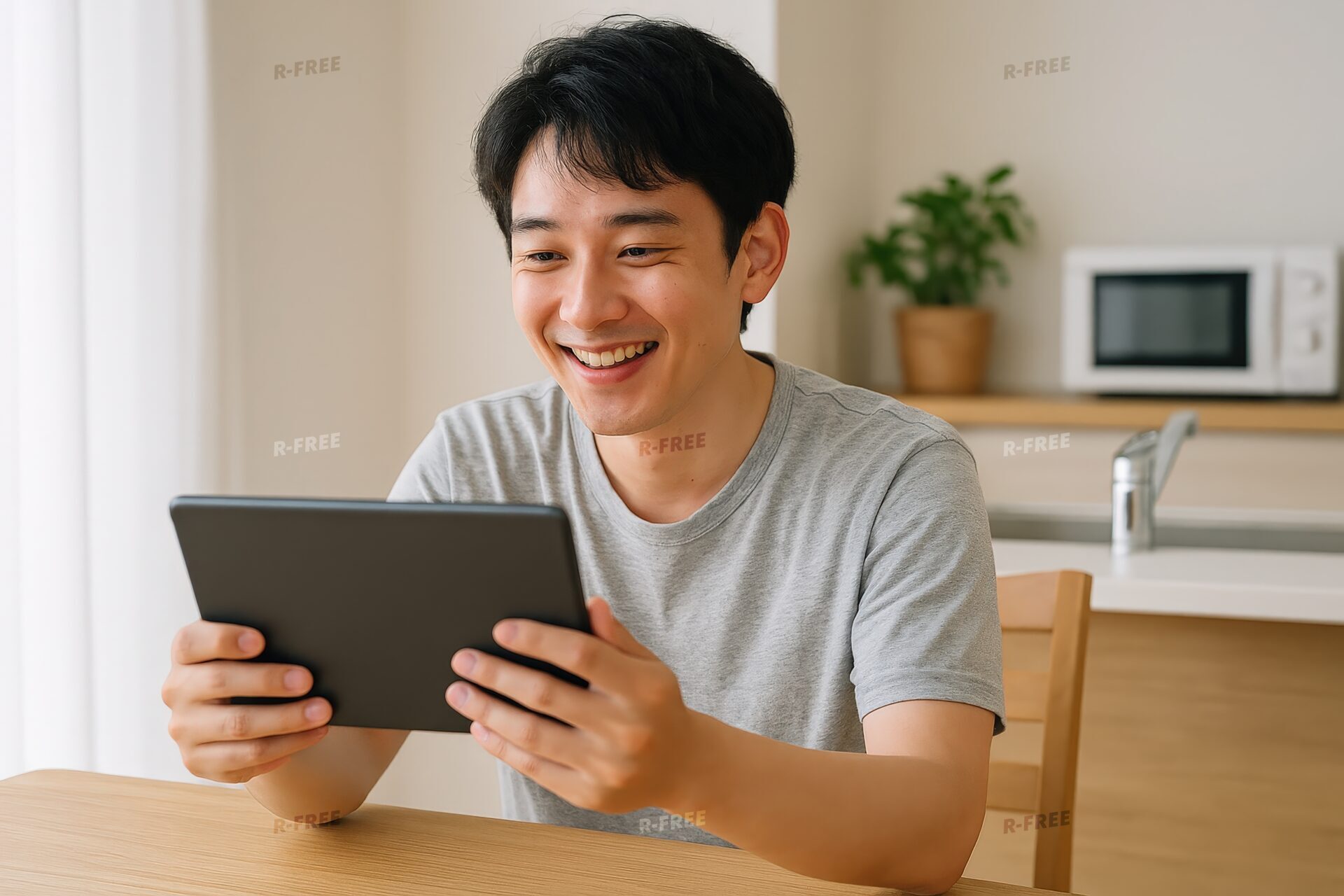 ダイニングテーブルで笑顔でタブレットを操作する男性