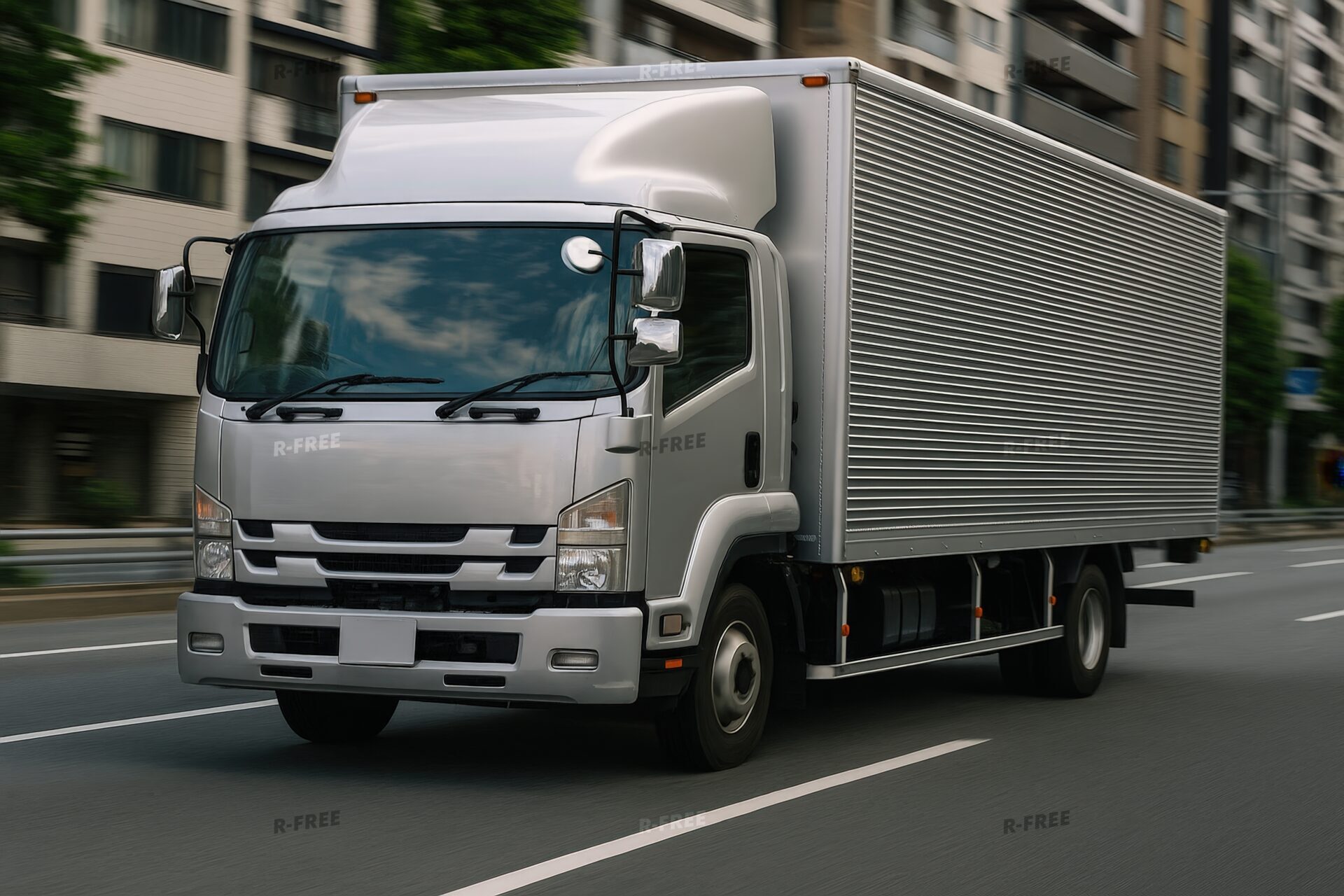 都市部を走行するシルバーの中型トラック