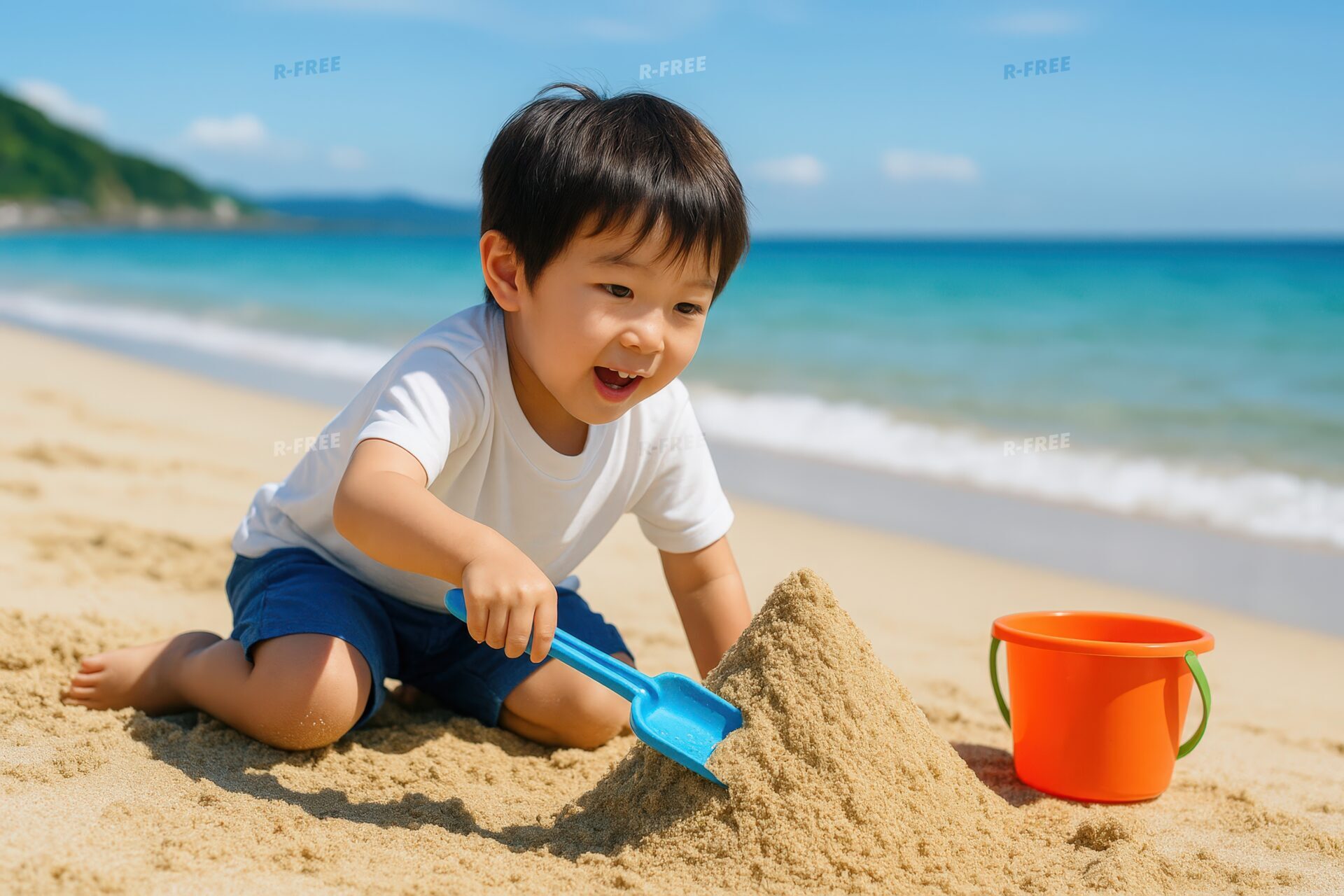 スコップで砂山を作る笑顔の男の子