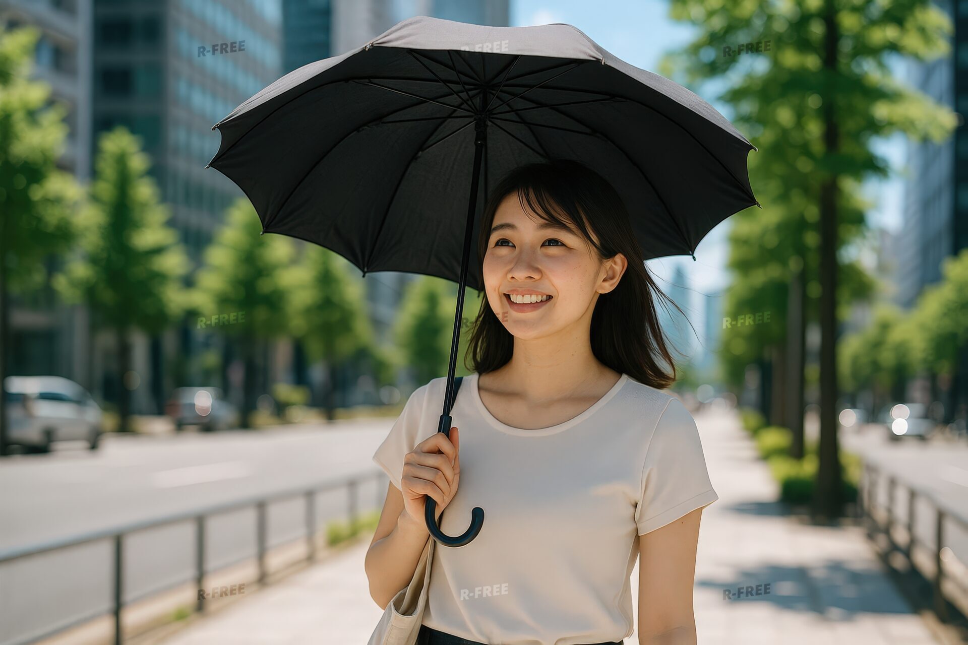 黒い日傘をさして笑顔で歩く若い女性