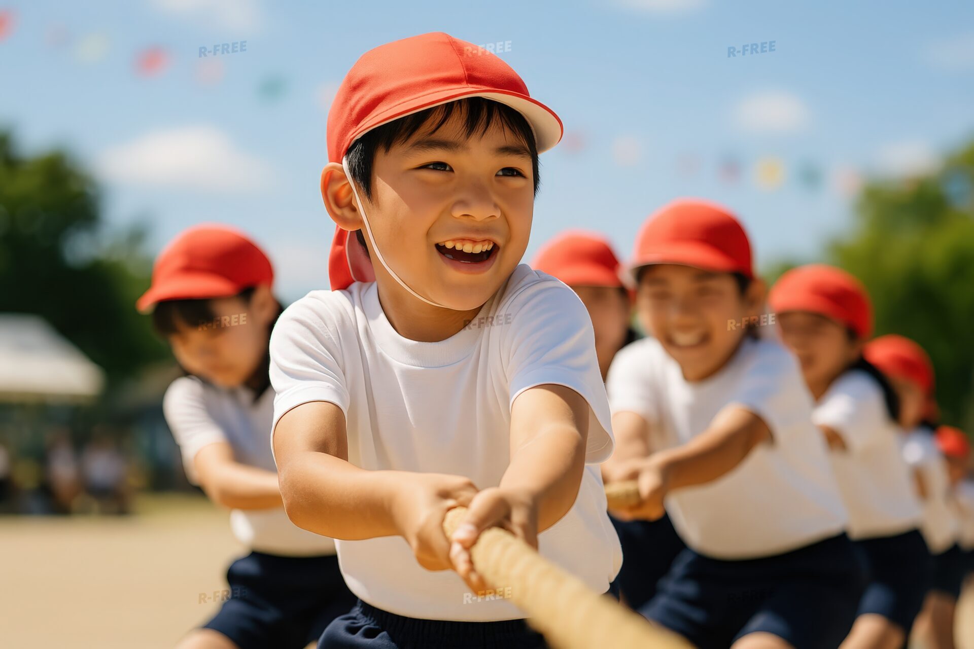 笑顔で綱引きをする小学生の男の子と仲間たち