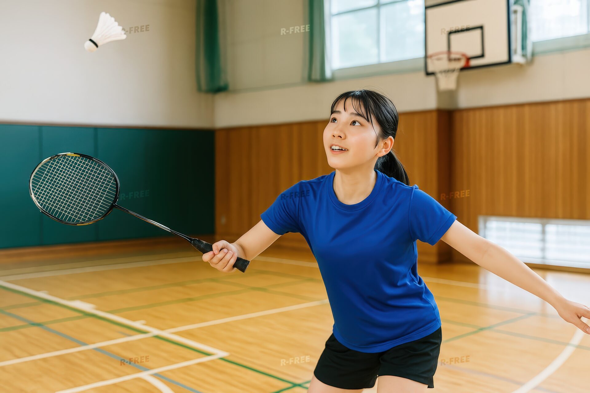シャトルを見つめてバドミントンの構えをする女子学生