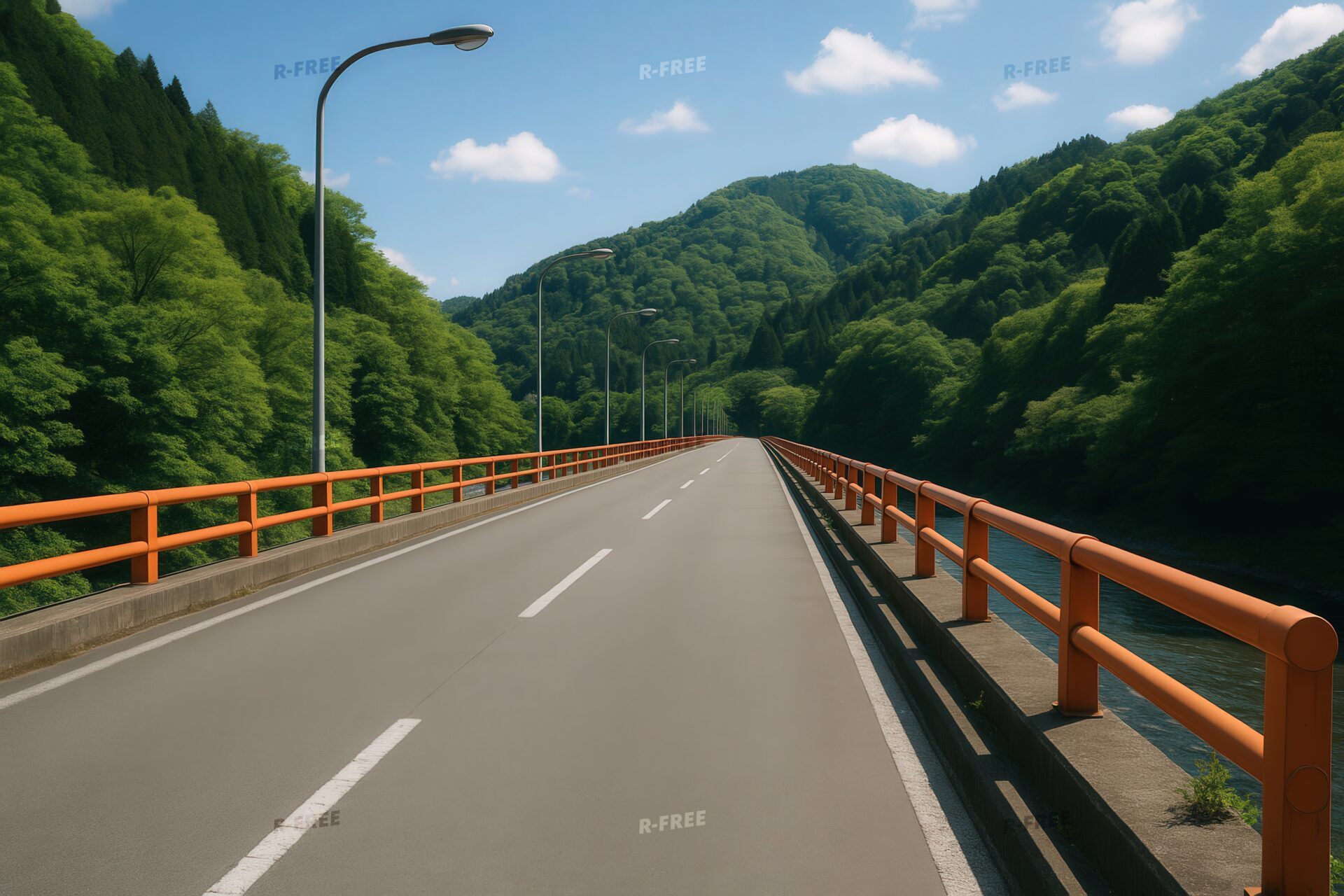 オレンジの欄干が並ぶ山間の道路橋と夏の青空