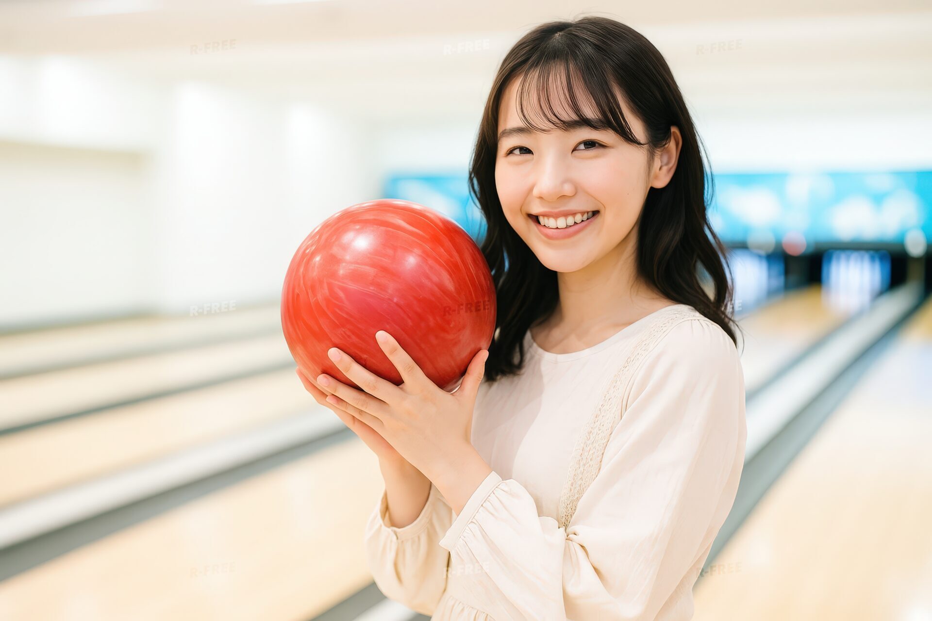 ボウリングボールを両手で持って微笑む女性