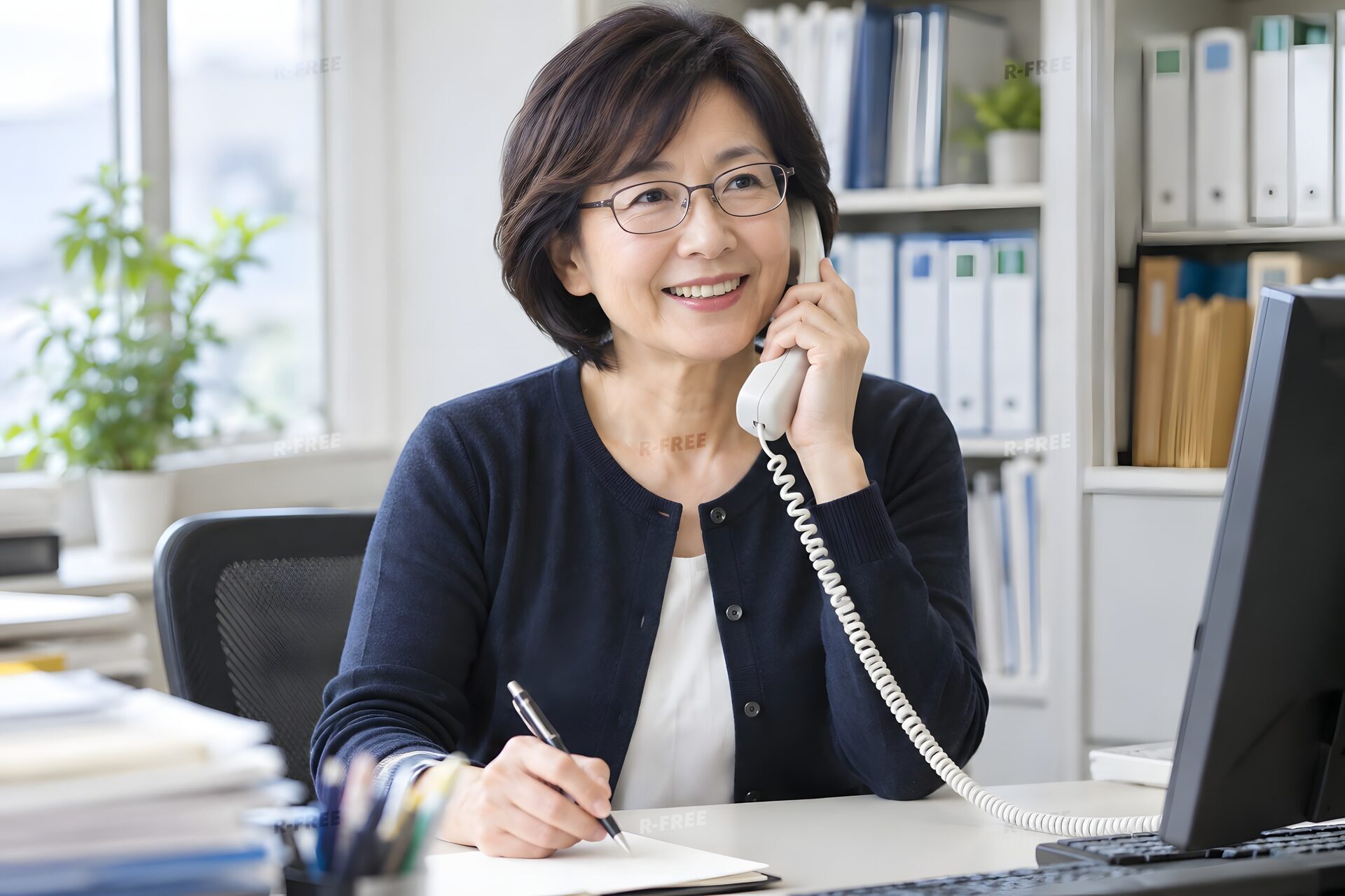 笑顔で電話応対をする眼鏡の50代女性