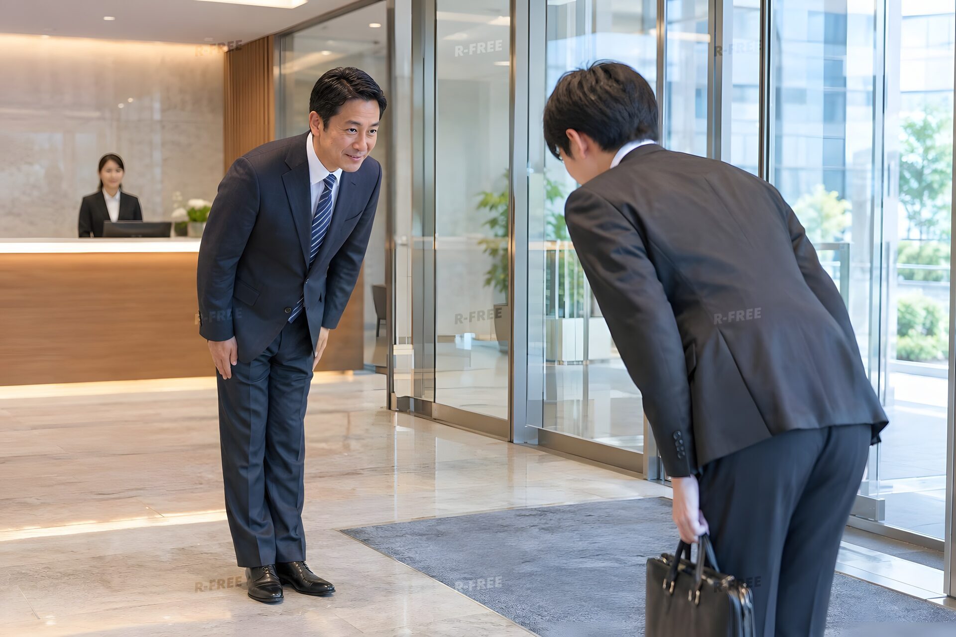 オフィスの入口で来客と互いにお辞儀をして迎える40代男性