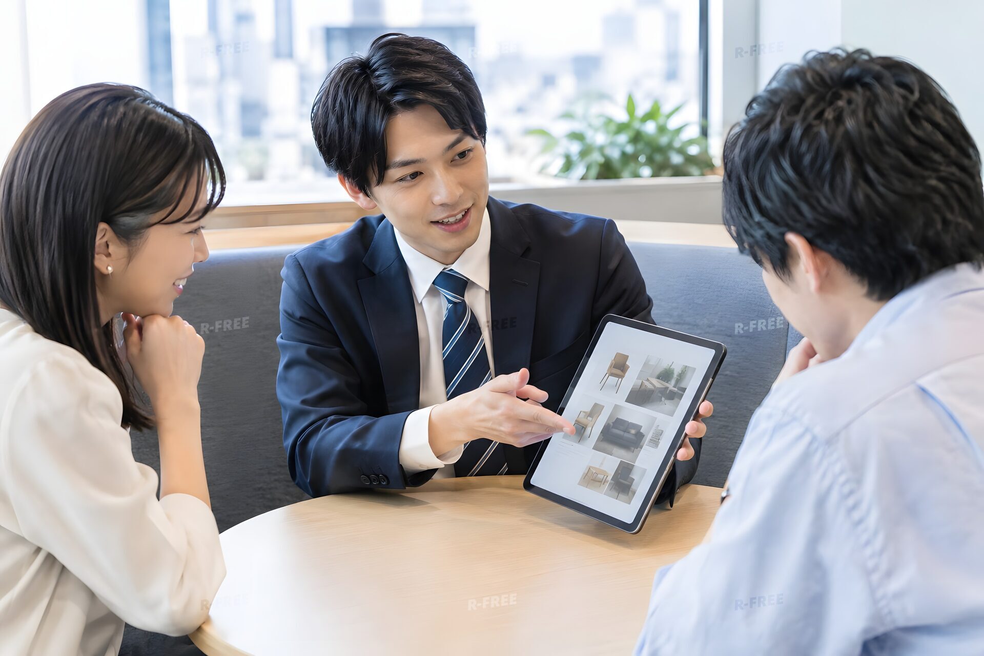 小さな商談ブースでタブレットのカタログを見せる20代の営業担当