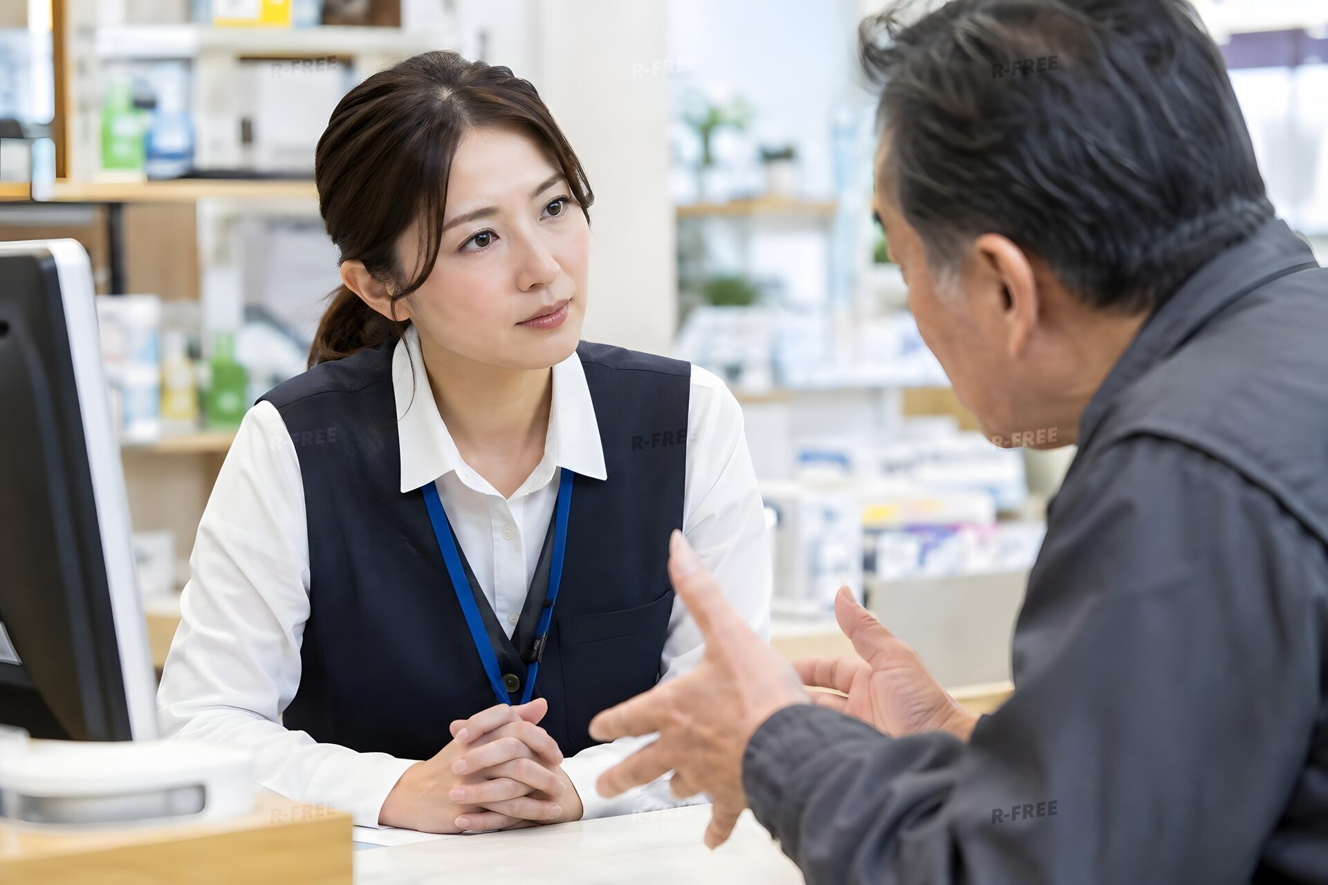 カウンターで怒った客の話を落ち着いて聞く30代の女性担当者