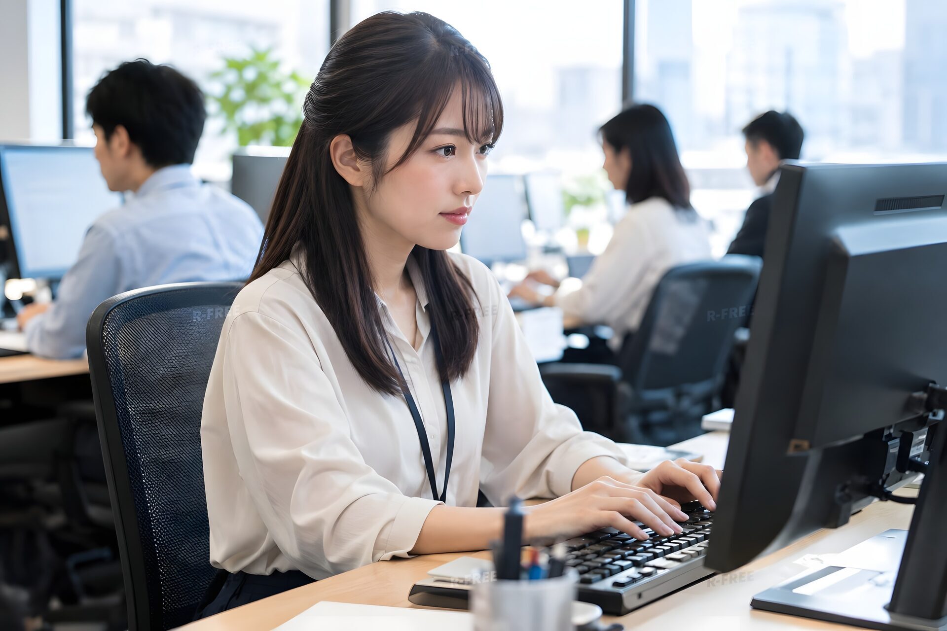 オープンオフィスのデスクでパソコンに向かう20代女性