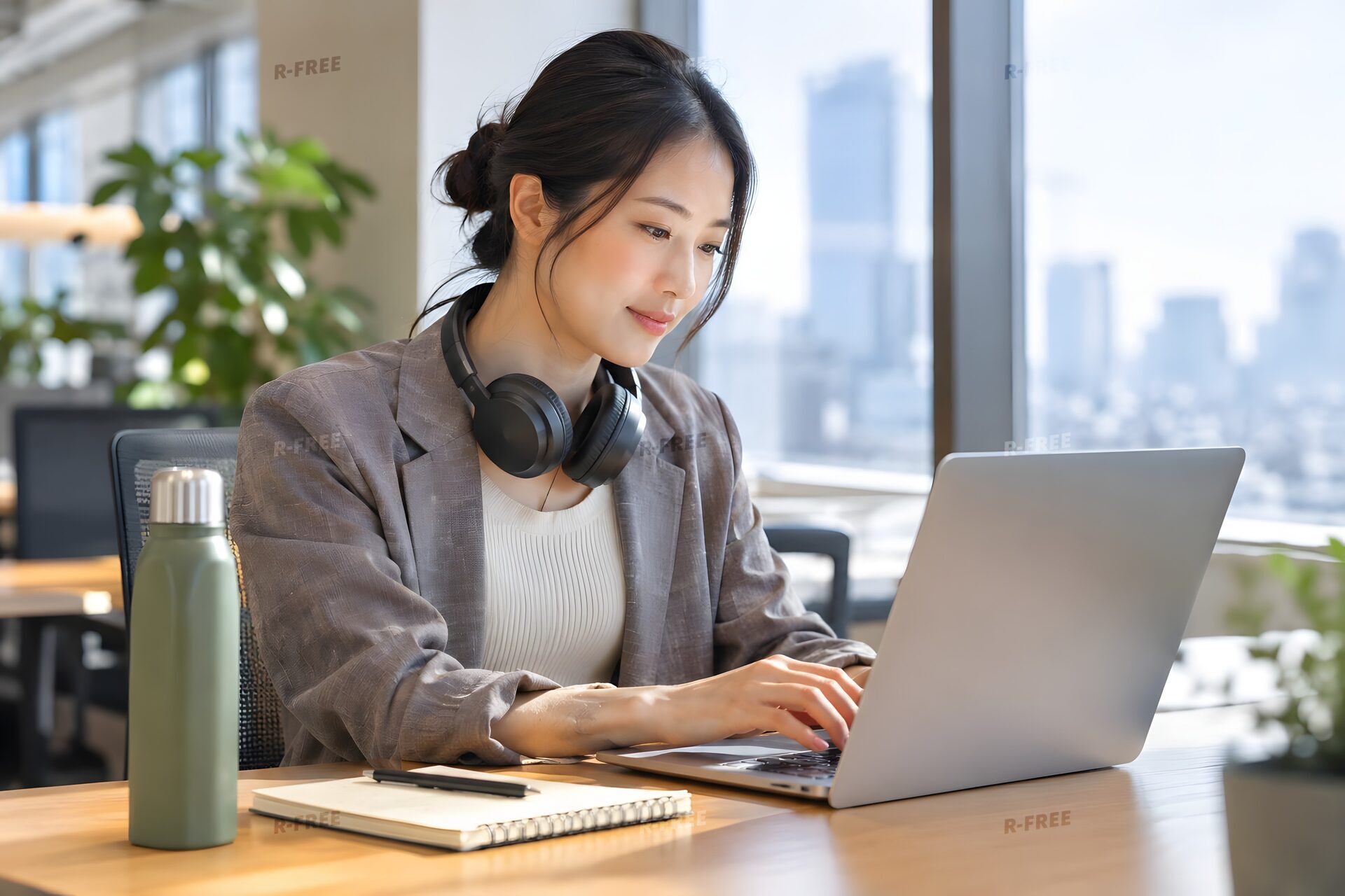 窓際のフリーアドレス席でノートパソコンに向かう30代女性