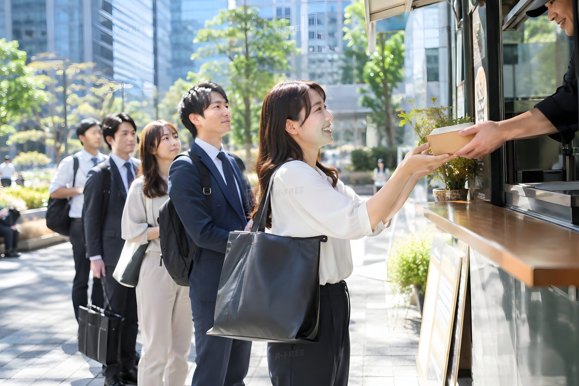 ランチタイムのオフィス街でキッチンカーに並ぶ社員たち