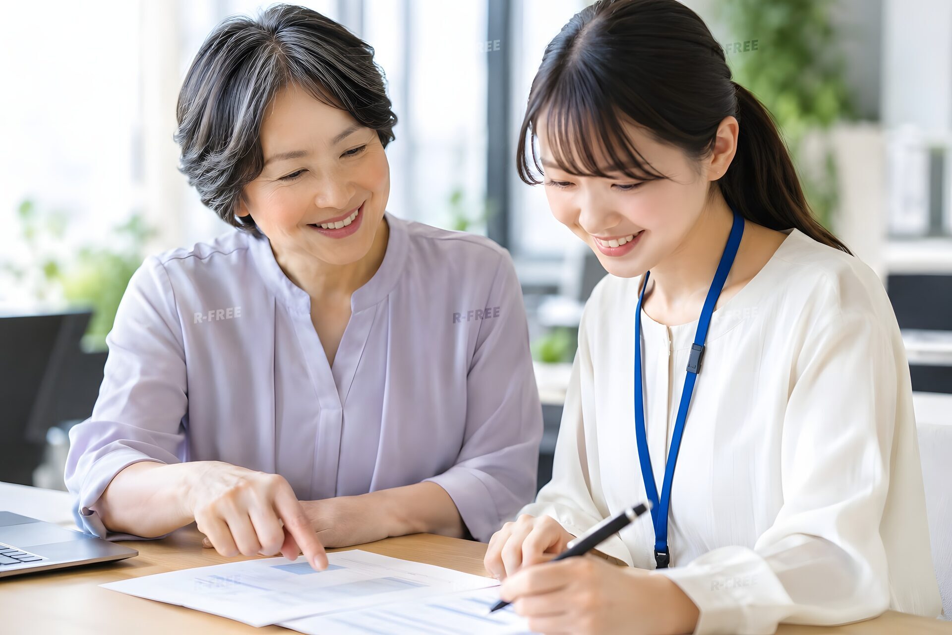 若手社員に書類を指して教える60代の女性ベテラン